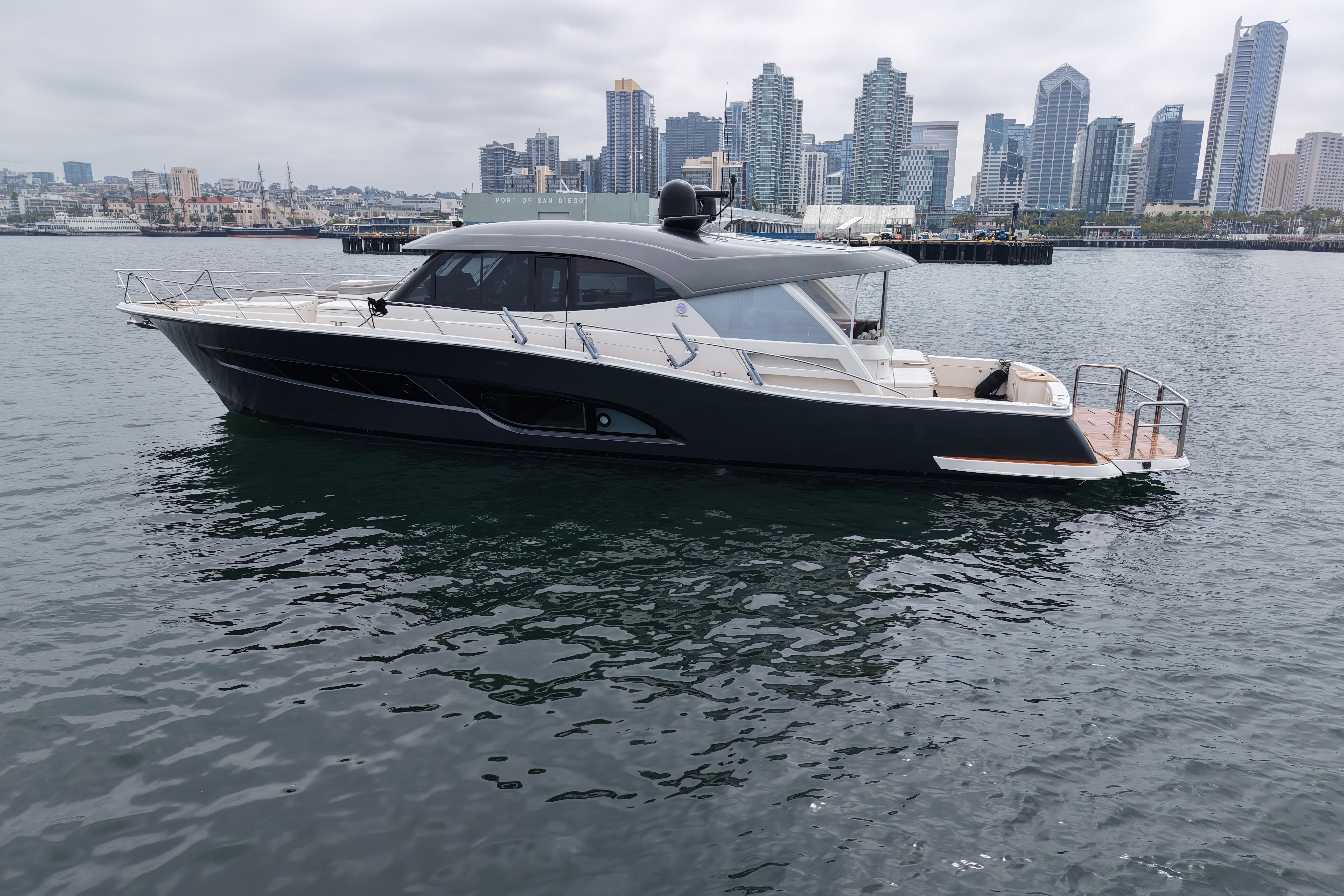 2023 Riviera 645 SUV yacht on water with city skyline backdrop.