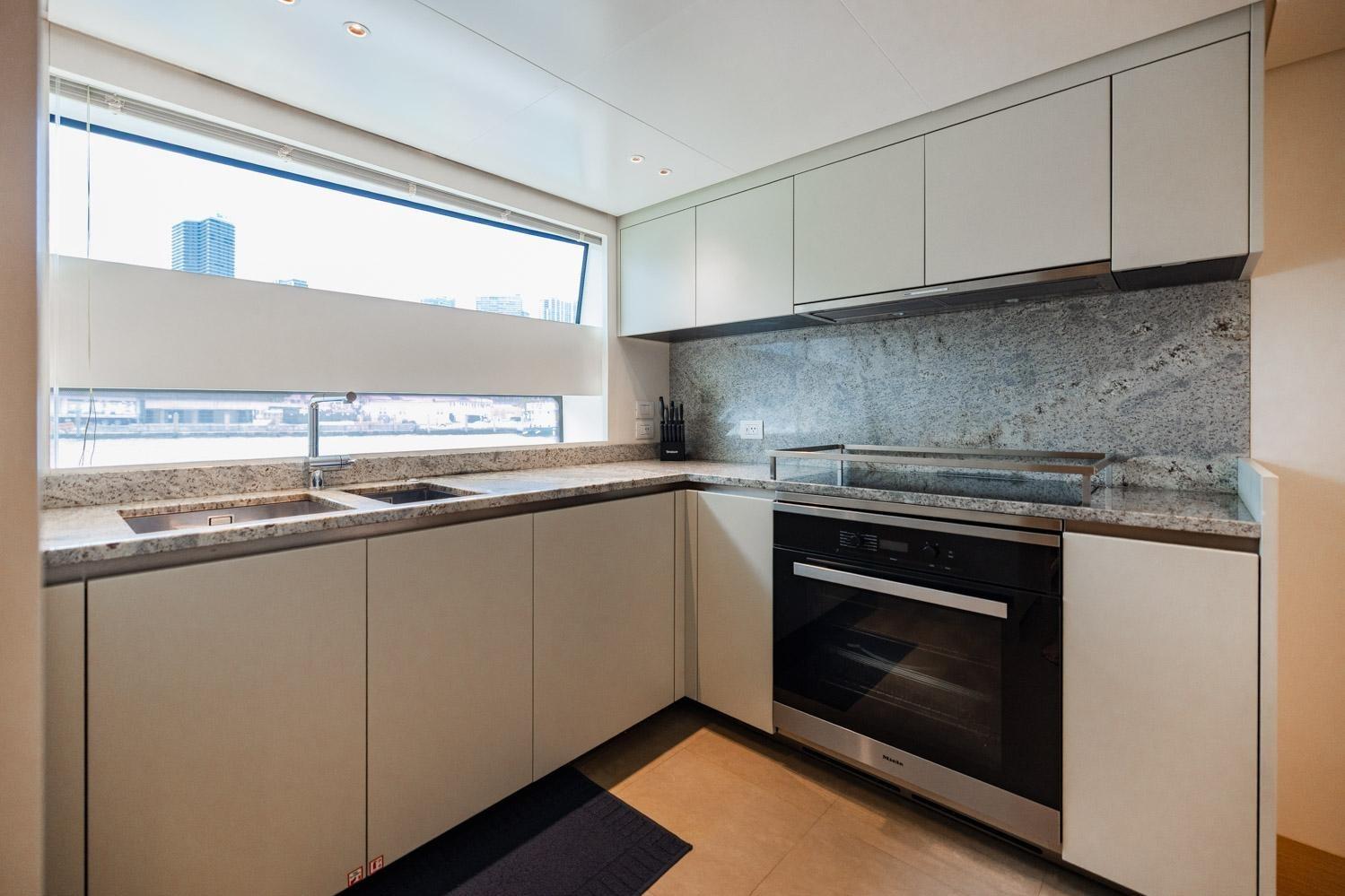 Modern kitchen in 2022 Sanlorenzo SD96 yacht with sleek cabinetry and granite countertops.