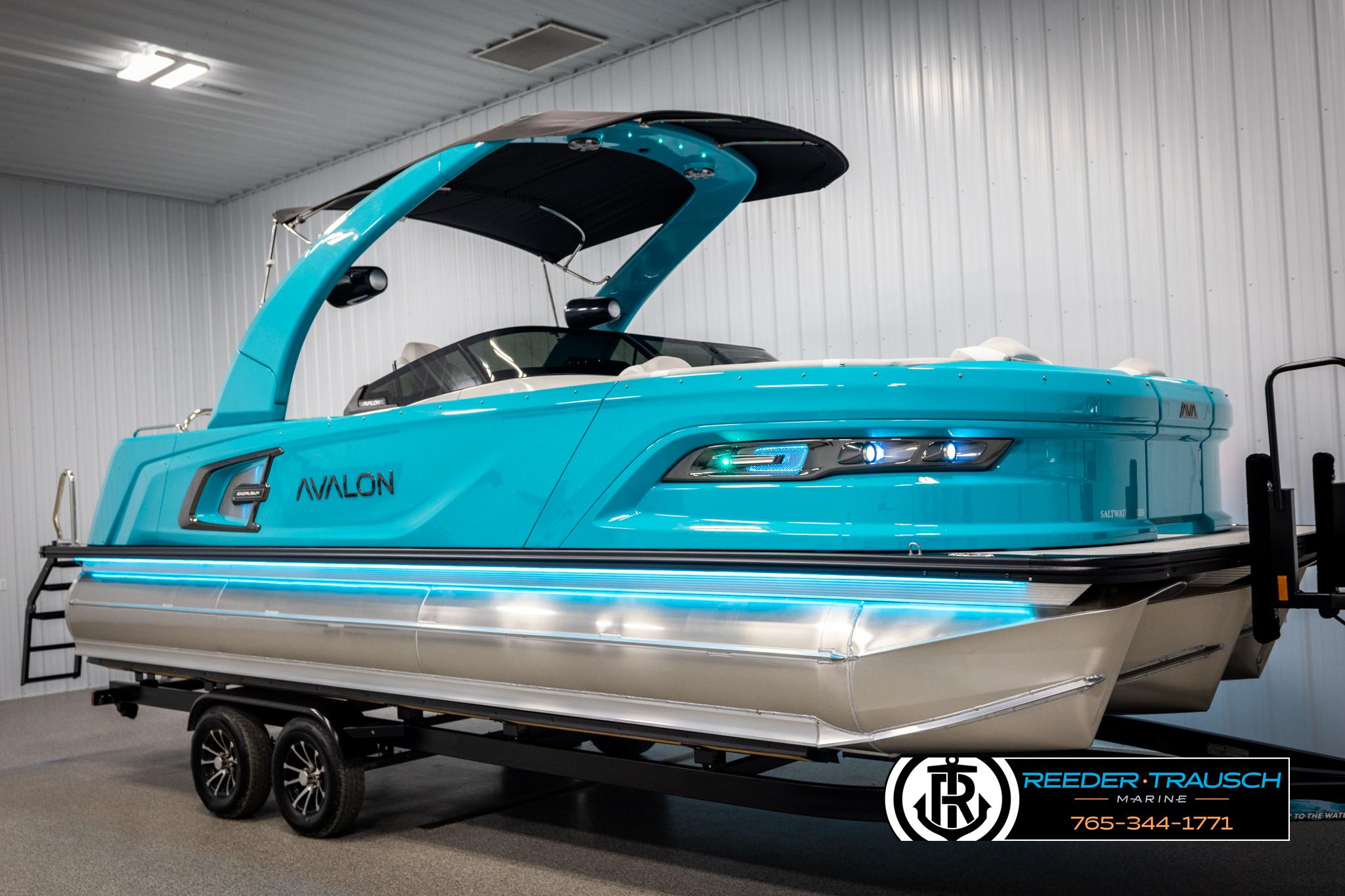 2025 Avalon 2585 Excal VRBW pontoon boat in vibrant blue, displayed indoors on a trailer.