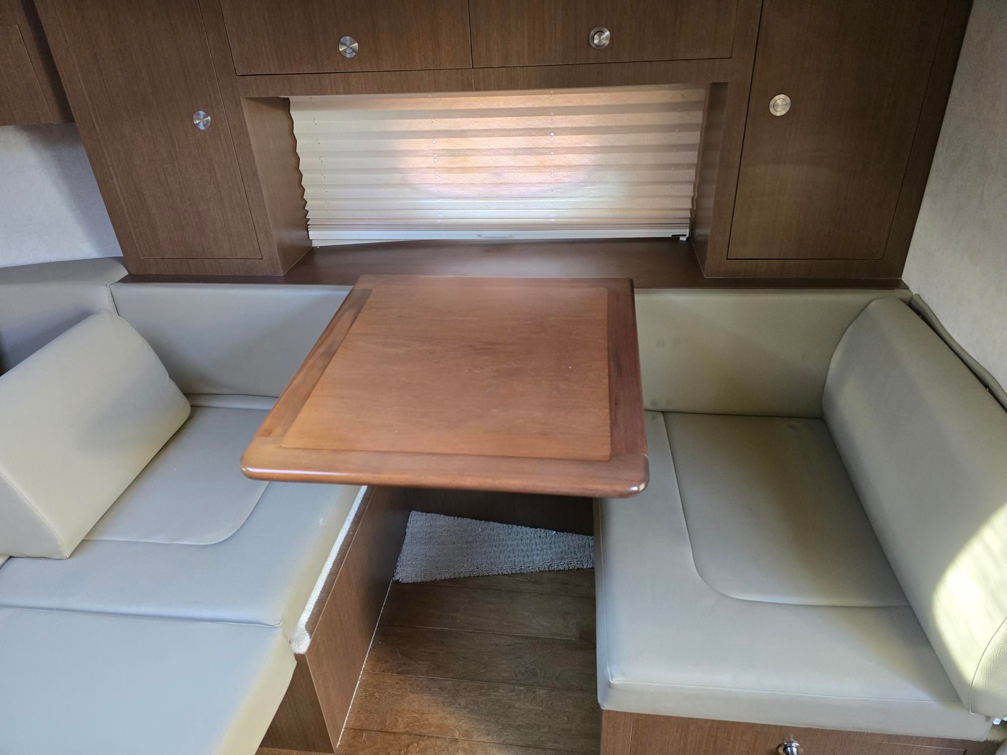 Interior of a Sea Ray Sundancer 310 with a wooden table and cushioned benches.