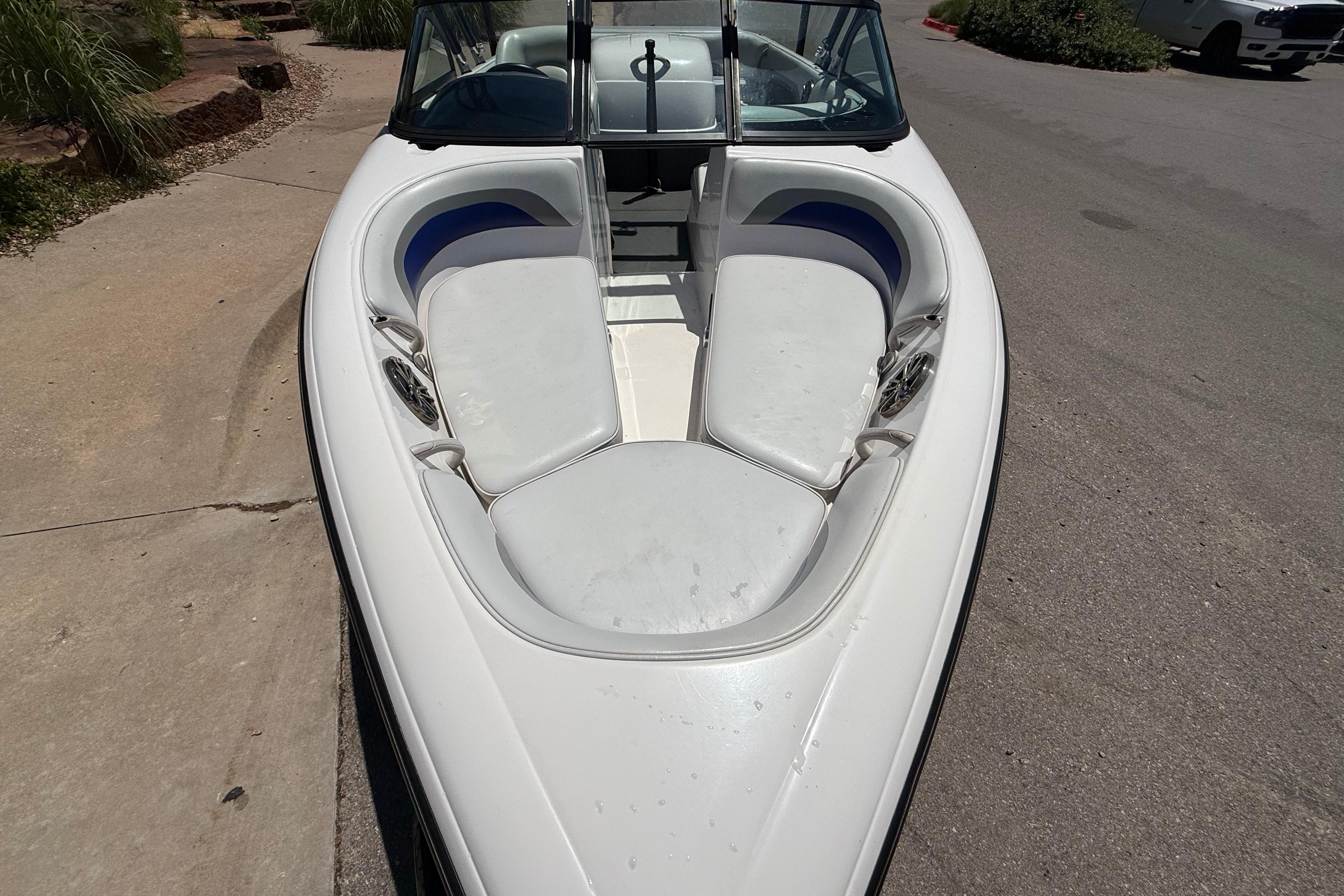 2001 Moomba Outback boat with white seating and windshield, parked on pavement.