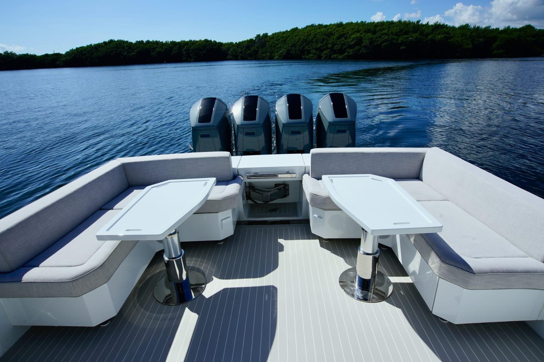 2024 Uniesse Exuma HTC5p yacht deck with seating and tables, overlooking serene water.
