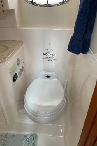 The image shows a clean, white boat toilet with a towel hanging nearby.