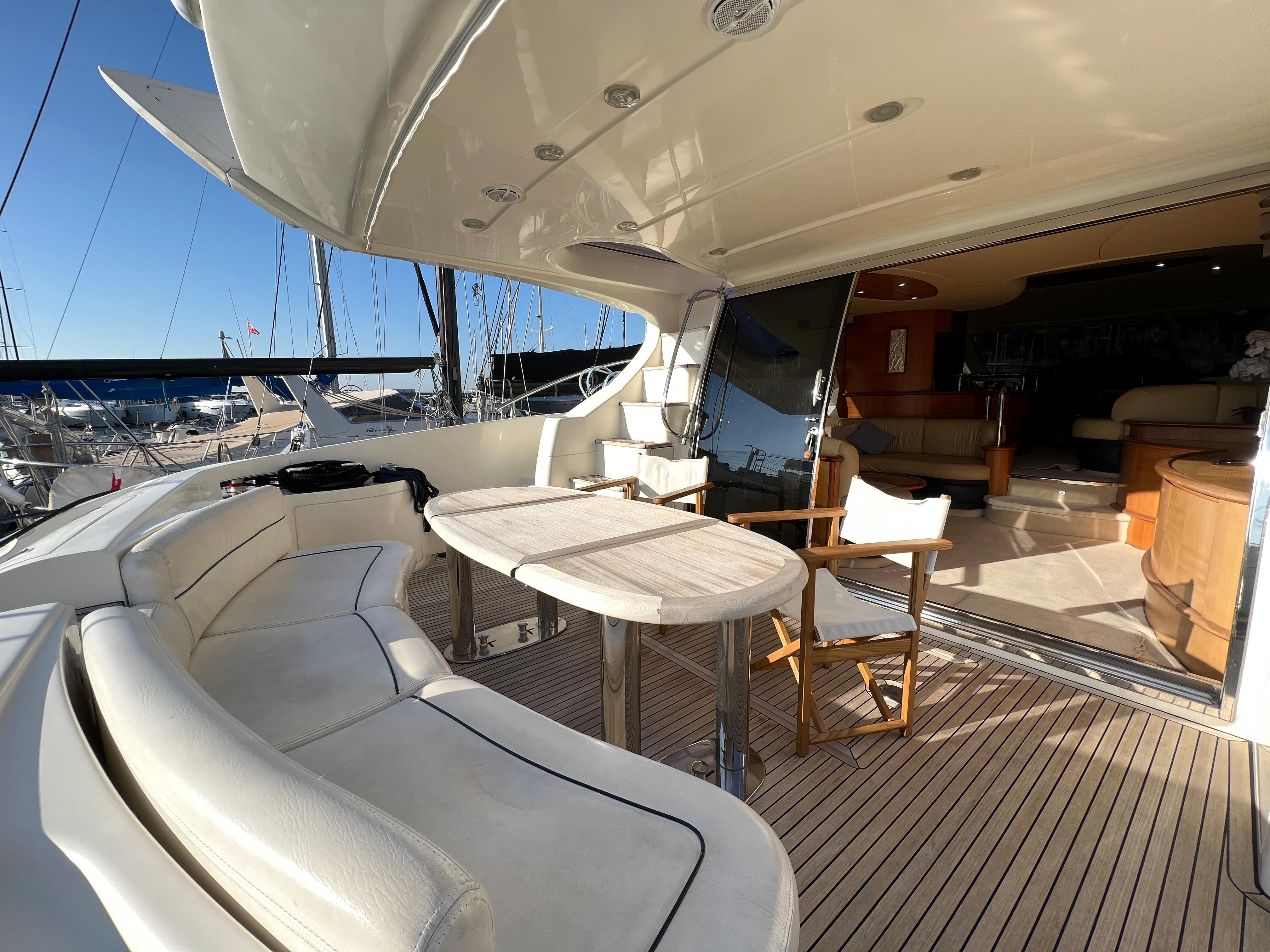 Luxurious 2005 Azimut 62 yacht deck with seating and table, docked at marina.