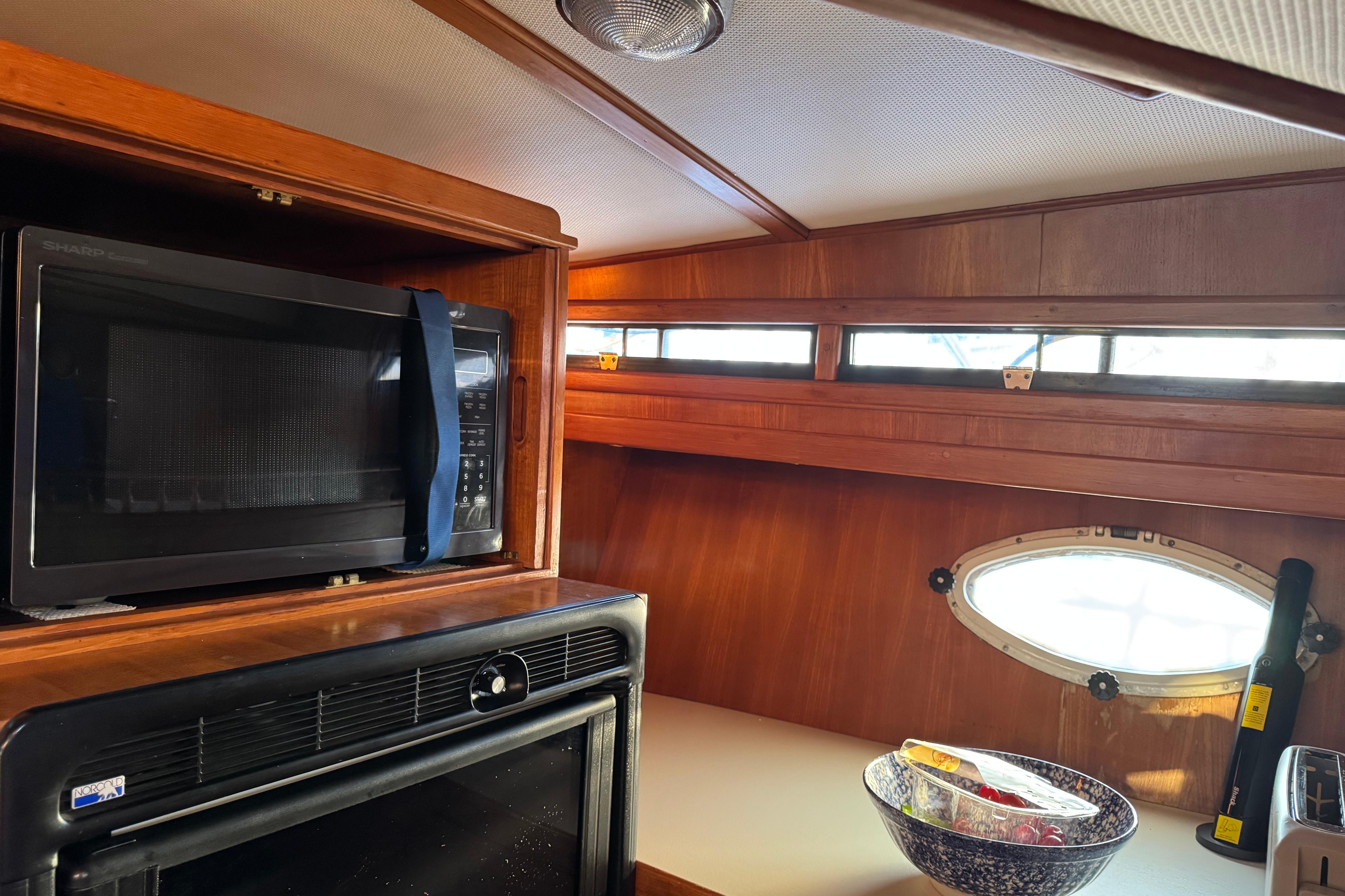 1987 President 37 yacht kitchen with microwave, oven, and porthole window.