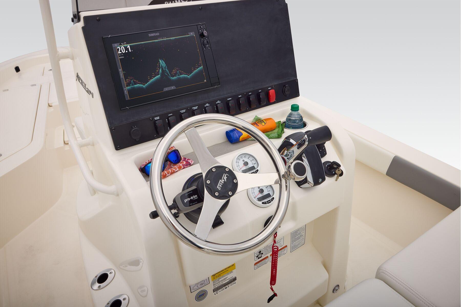 Helm of 2026 Mako 24 APEX boat with steering wheel and navigation display.