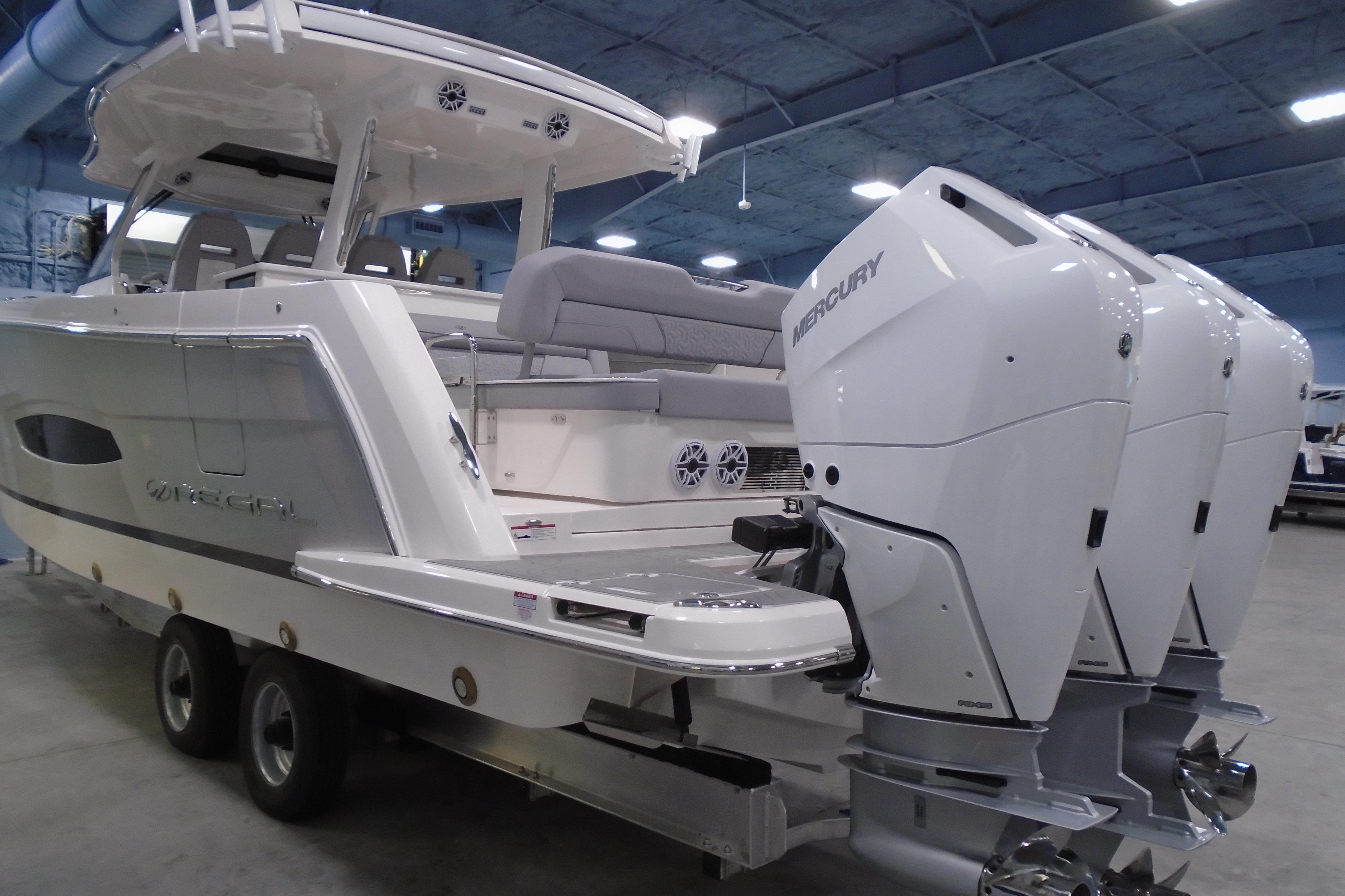 2026 Regal 38 SAV boat with triple Mercury engines in a showroom.
