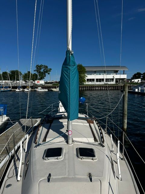 A 1985 Catalina 27 docked. The mast is covered with a blue cover.