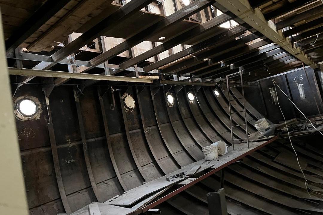 Interior of 1963 Custom SME Heureka ship under renovation, showing metal framework and portholes.