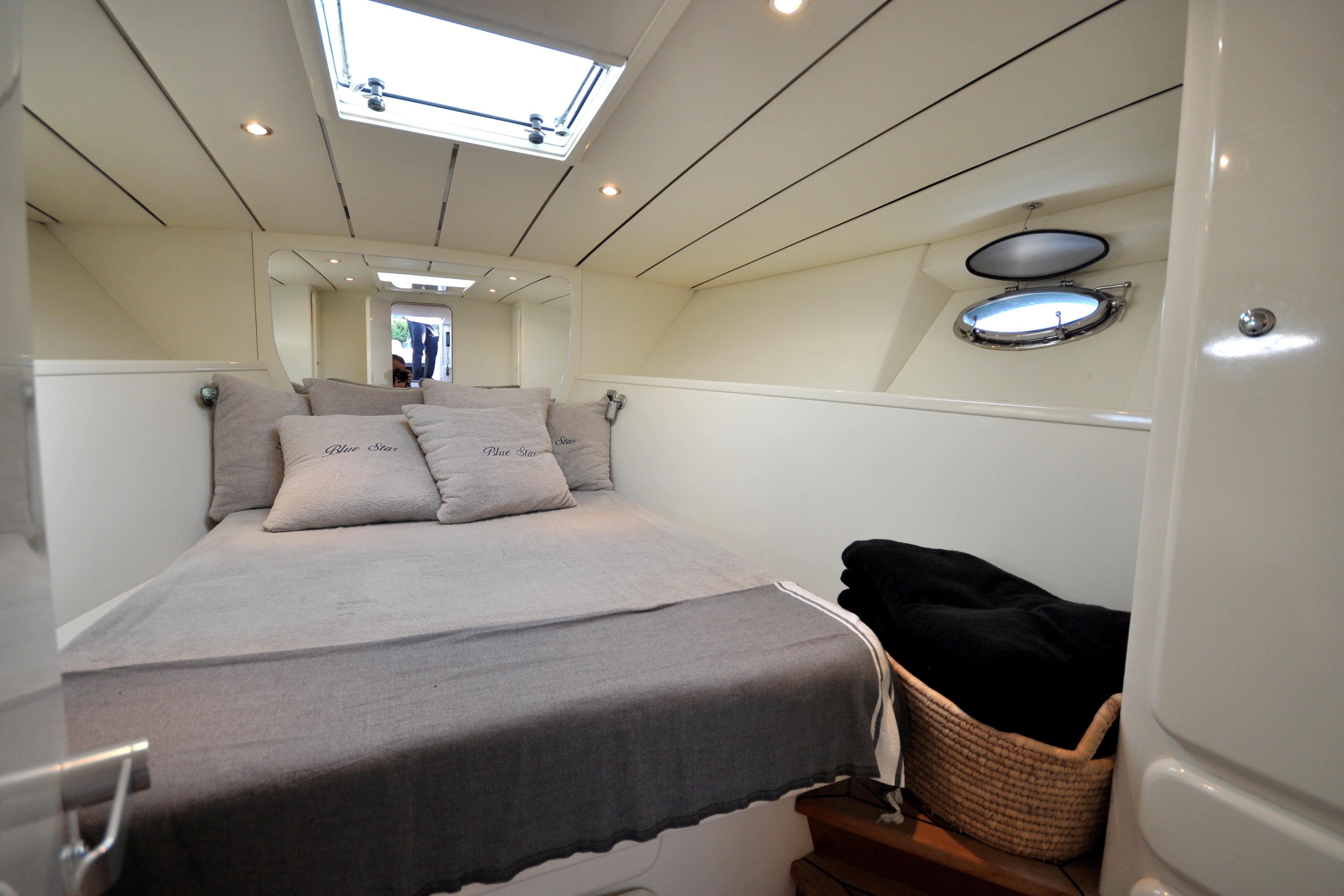 Luxurious cabin interior of a 1996 Itama 38 yacht with cozy bedding and porthole.