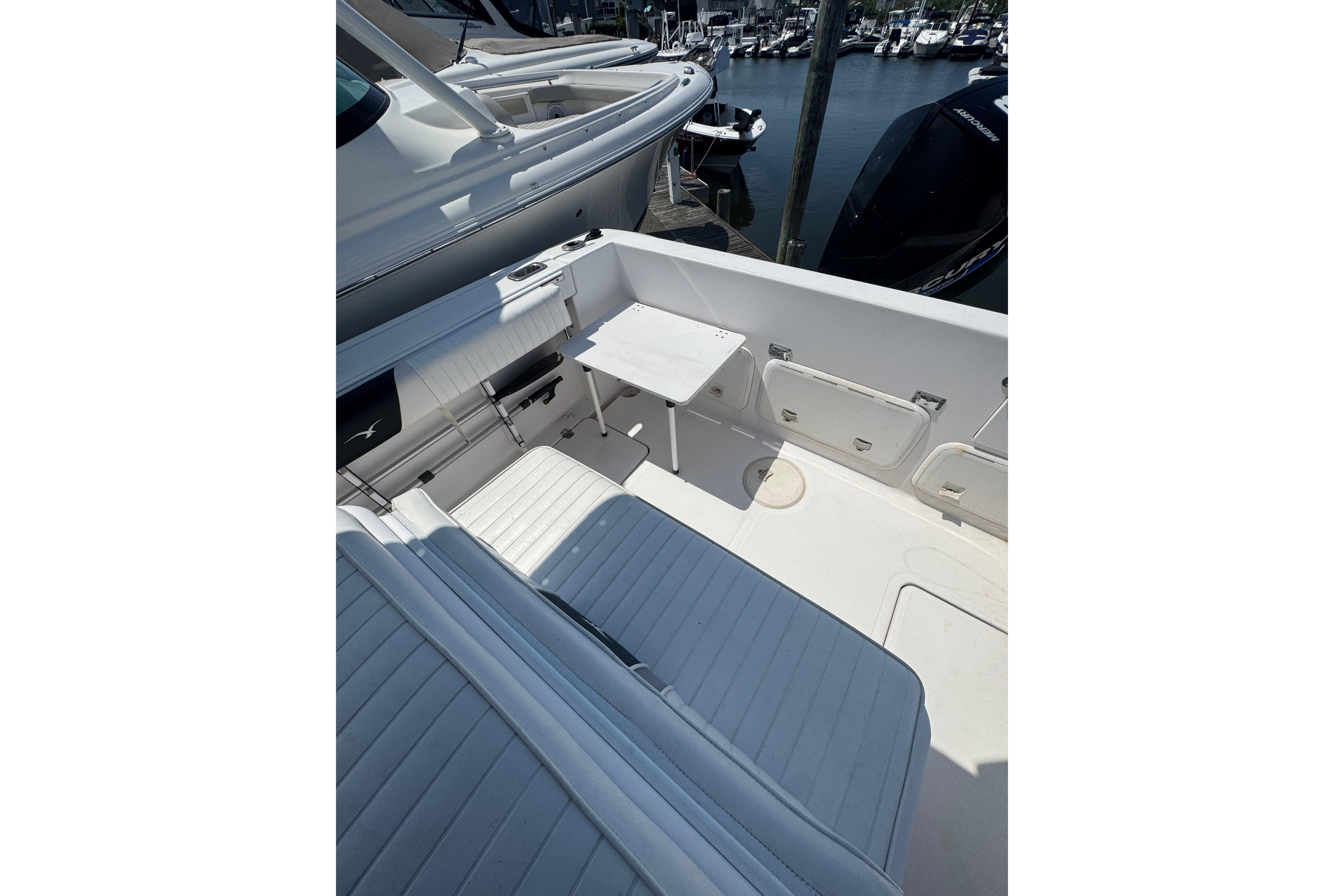 2002 Pro-Line 23 Sport boat interior with seating and storage compartments at a marina.