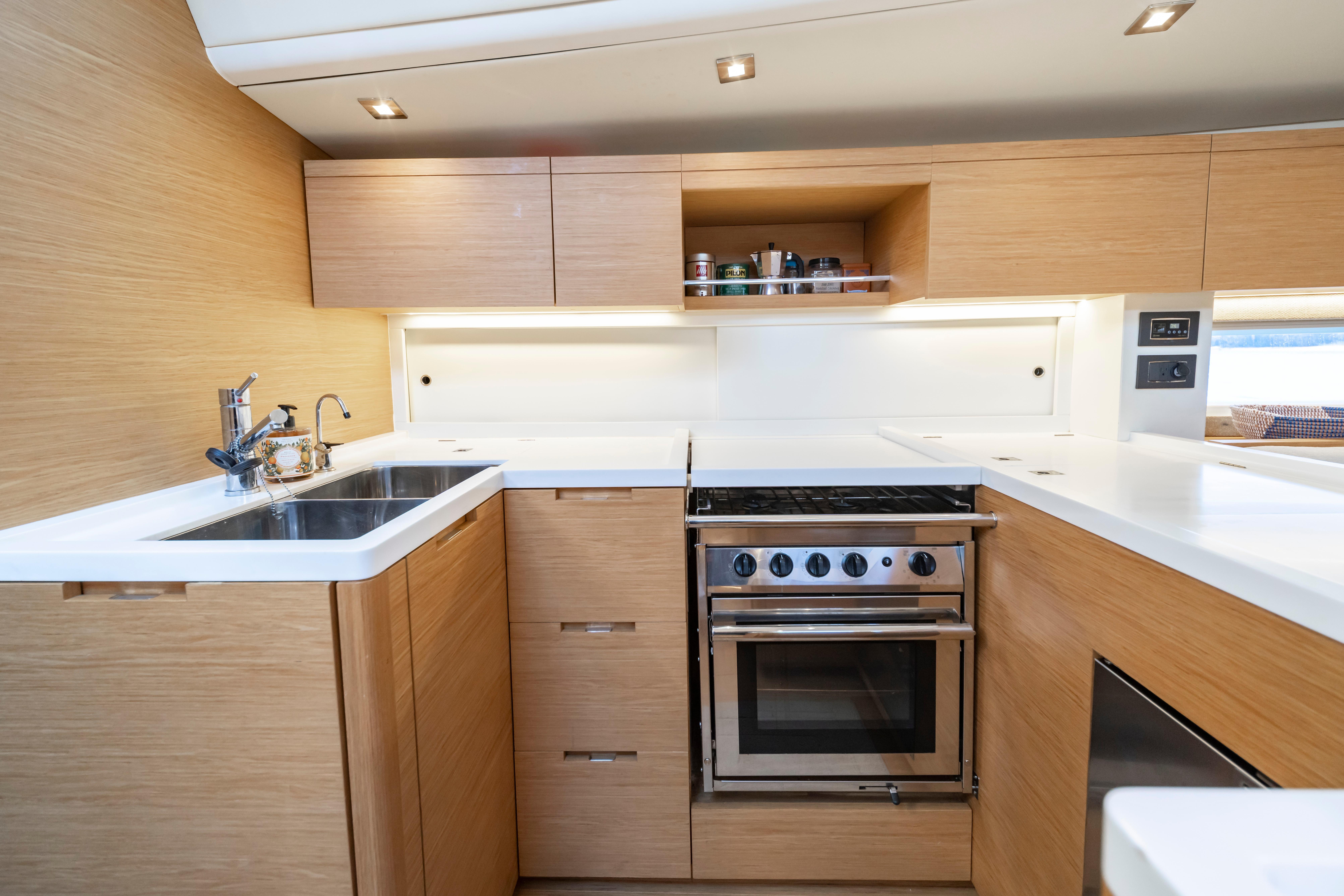 Modern kitchen interior of 2016 Grand Soleil 58 yacht with wood cabinetry and stainless steel appliances.