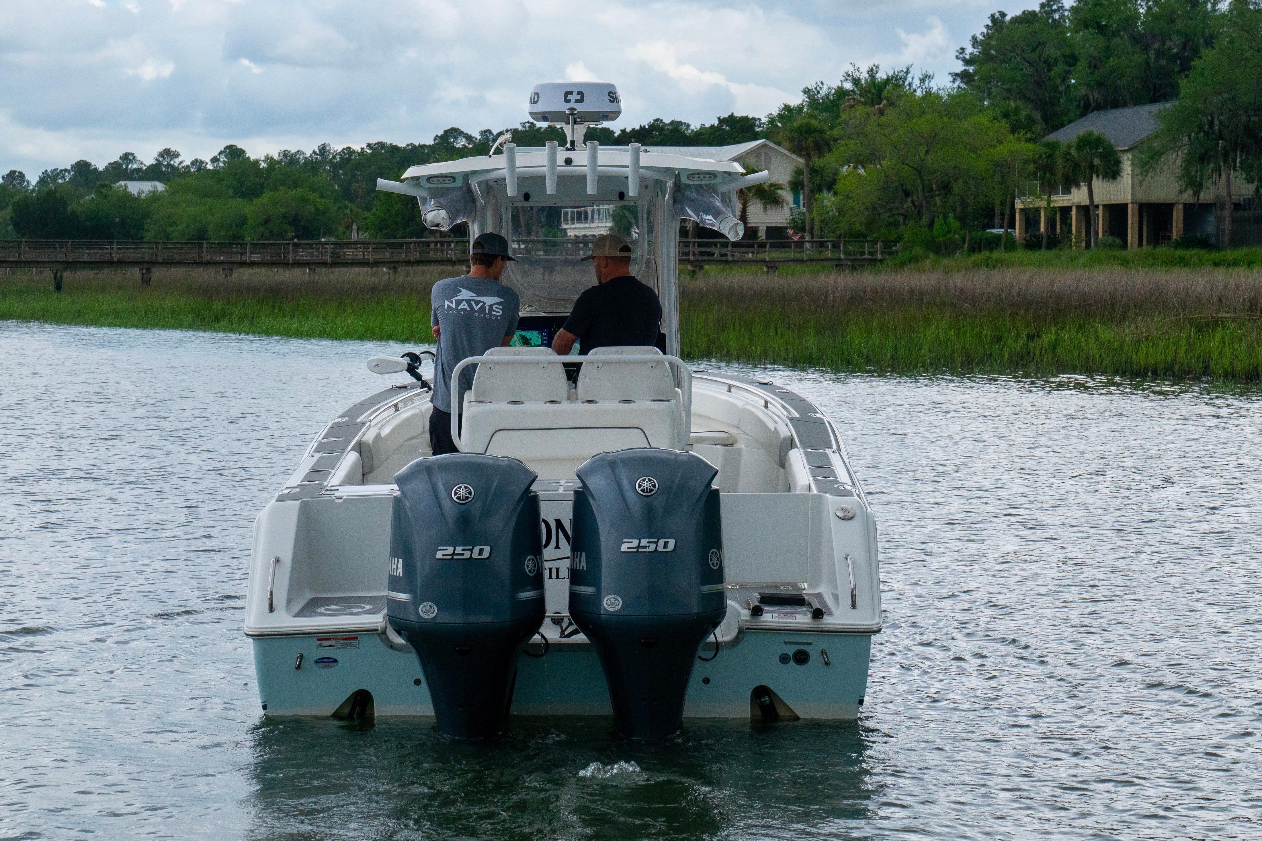 2014 Sea Hunt Gamefish 27 boat with dual Yamaha engines on a scenic waterway.
