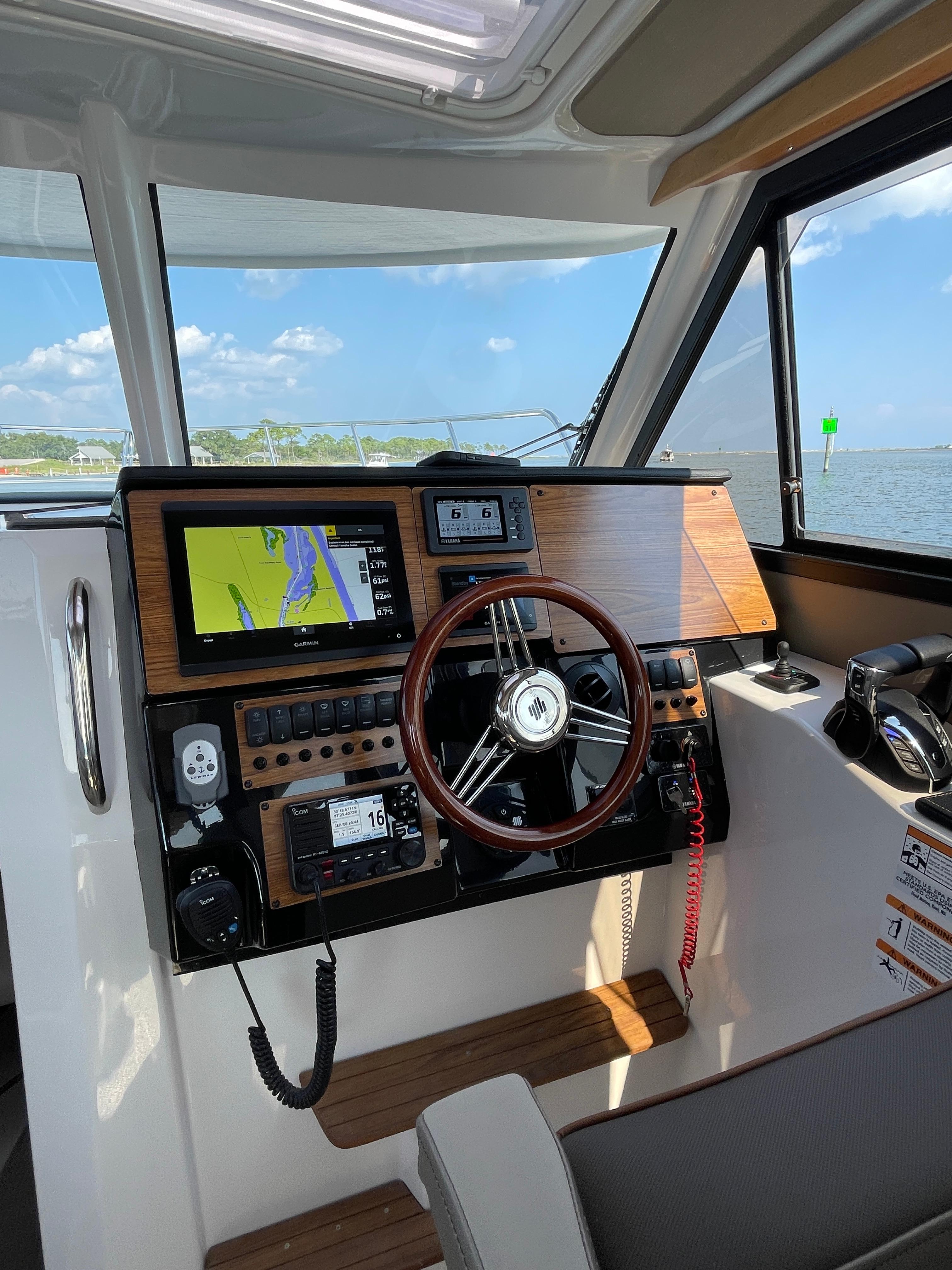 2026 Cutwater C-288 Coupe helm with navigation screens and steering wheel, overlooking water.