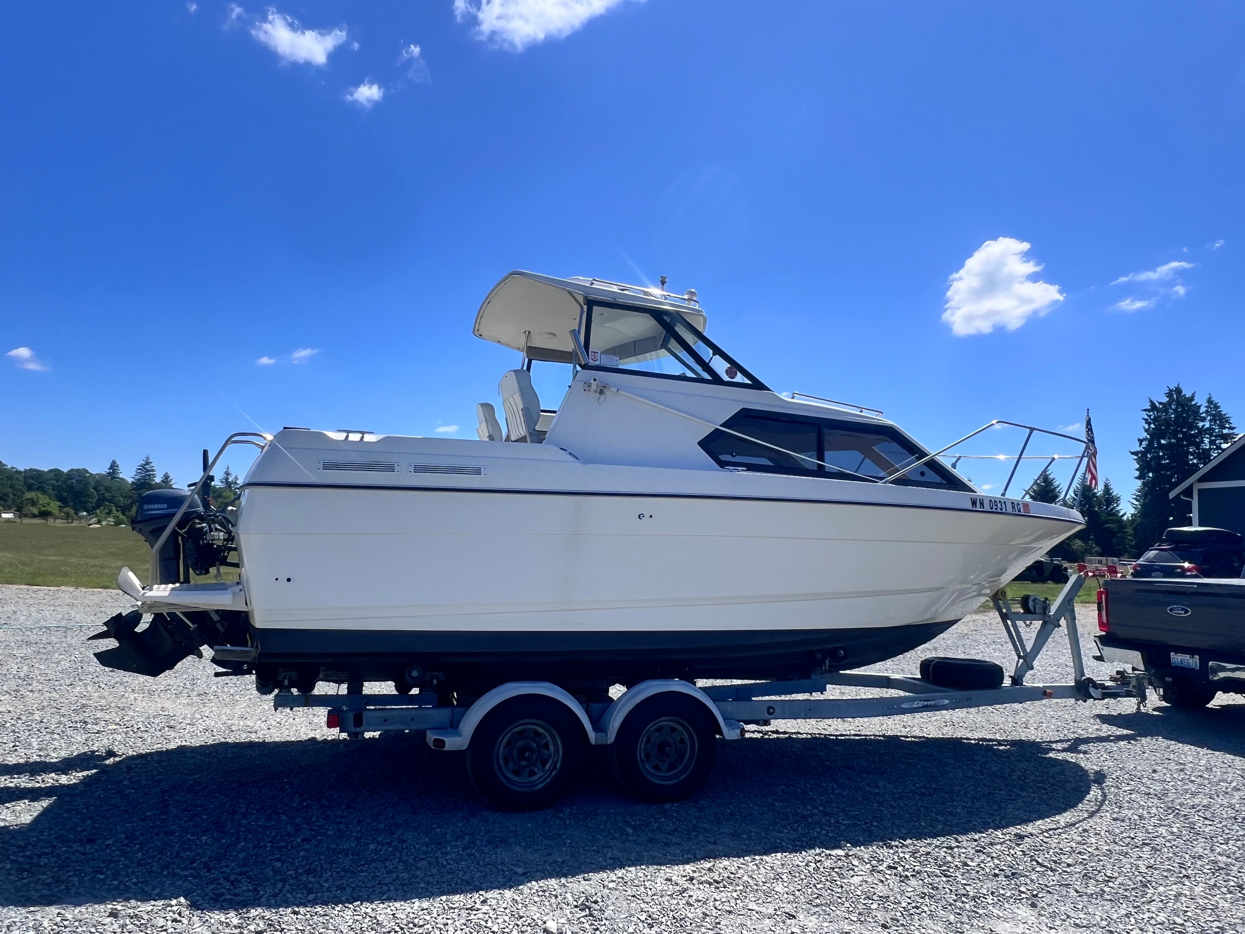 1997 Bayliner 2452 boat on trailer under sunny skies.