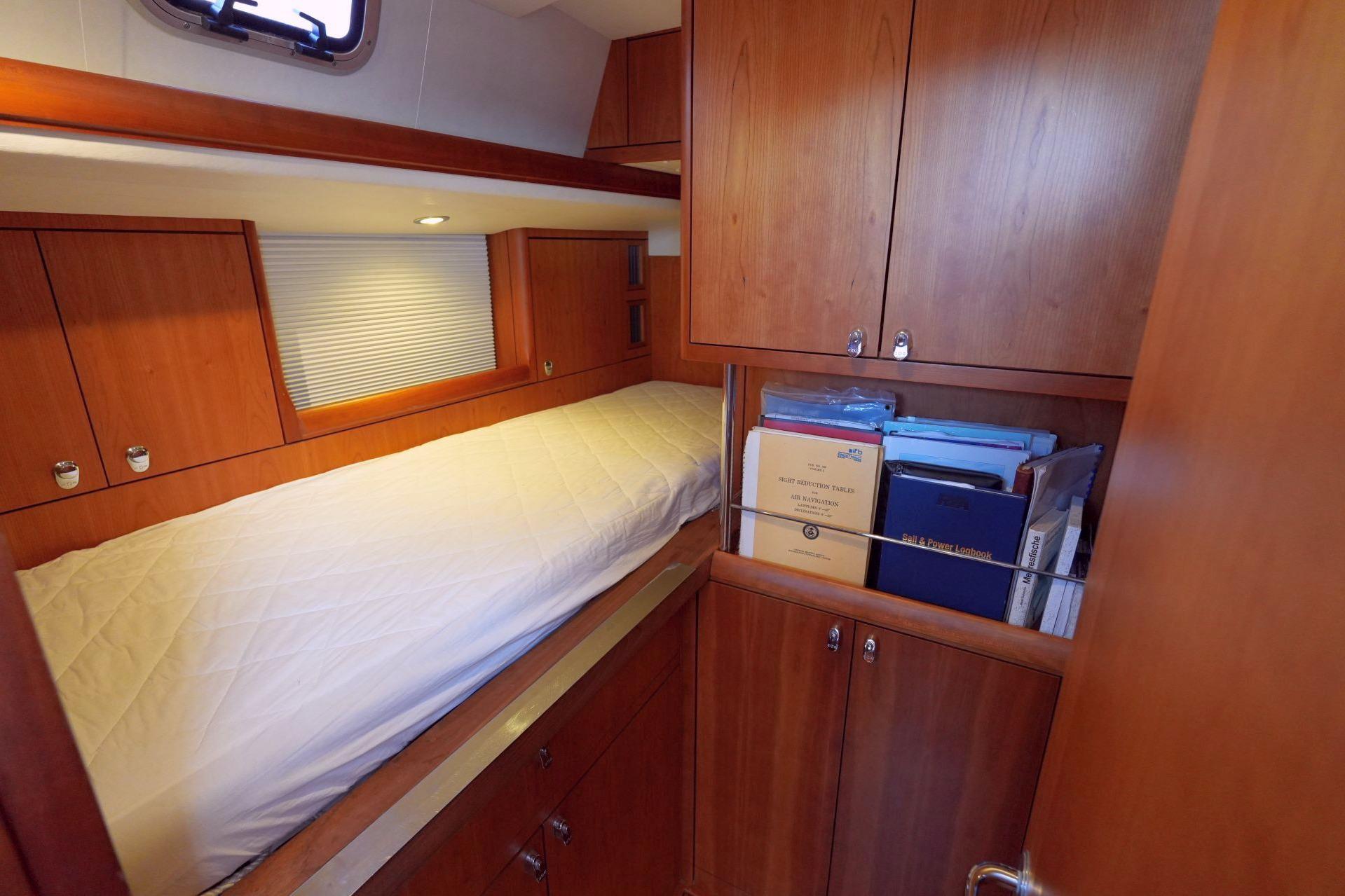 Cozy cabin interior of 2011 Oyster 575 yacht with wooden cabinetry and single bed.
