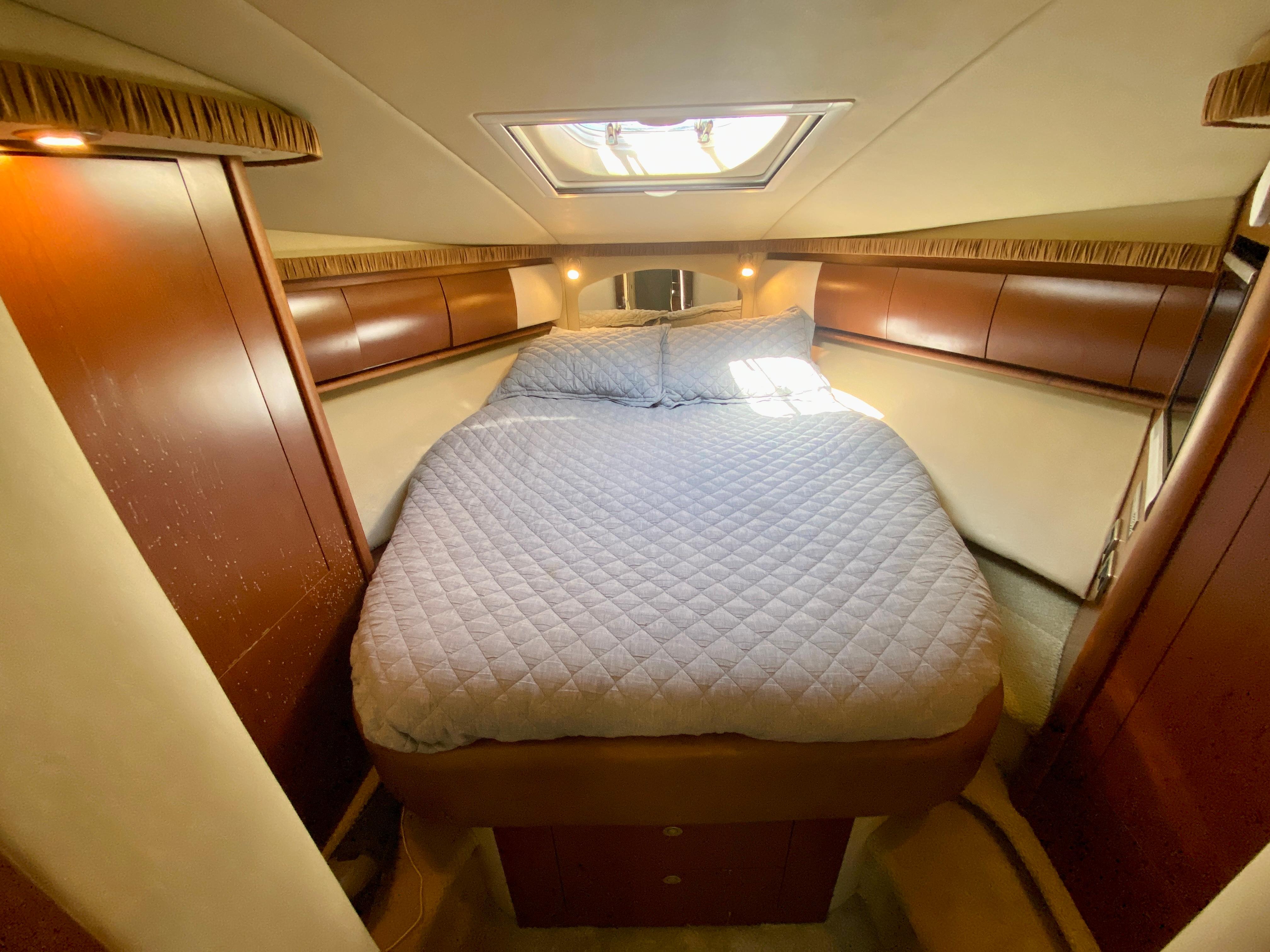 Luxurious bedroom in 2007 Sea Ray 44 Sundancer yacht with skylight and cozy bedding.