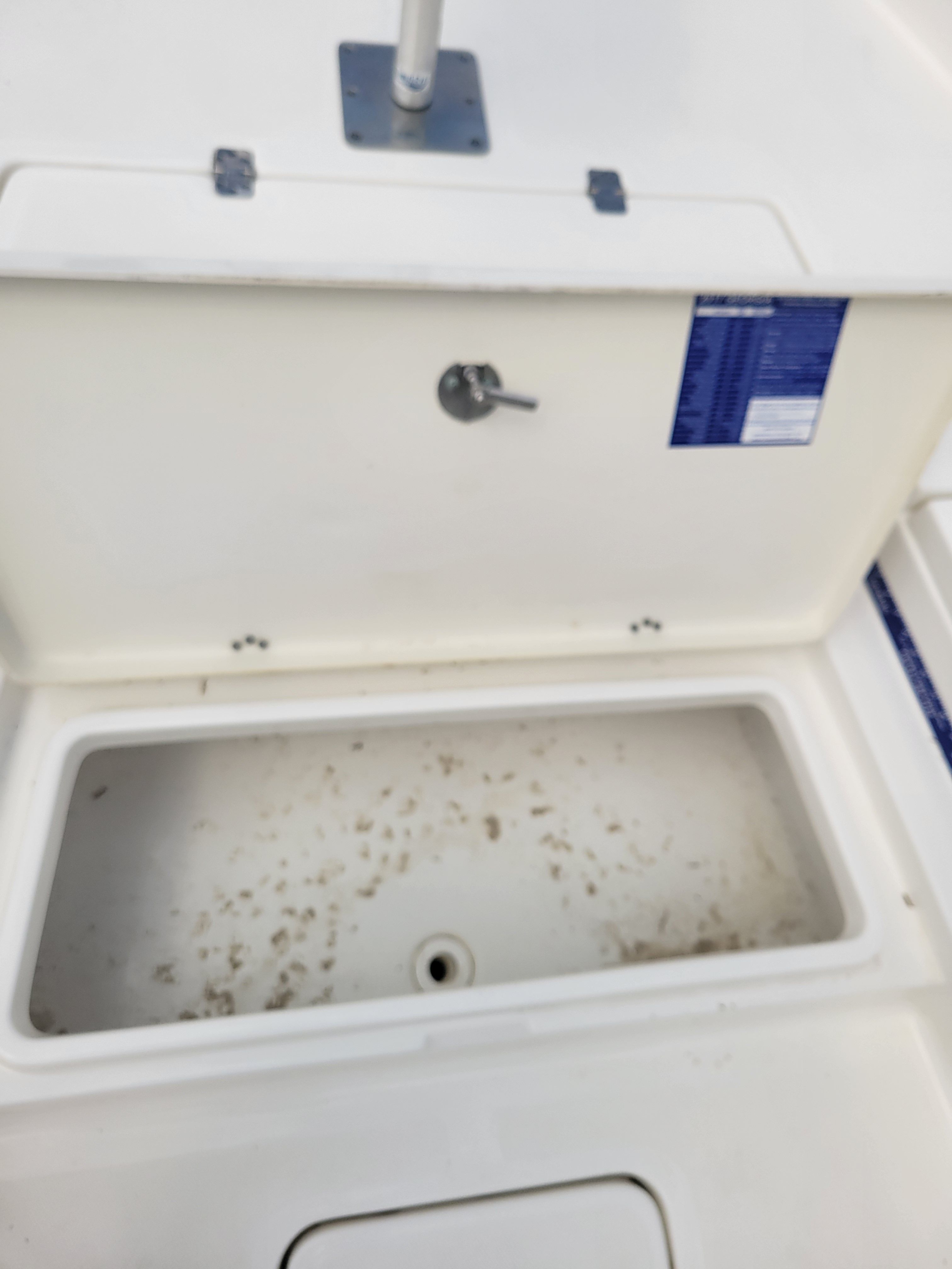 An open storage compartment on a boat with some dirt inside.