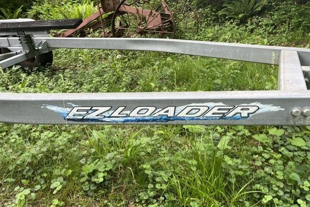 Trailer with "EZ Loader" logo in grassy area.