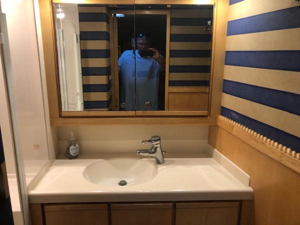 1997 Bertram Convertible bathroom with sink, mirror, and striped wallpaper.