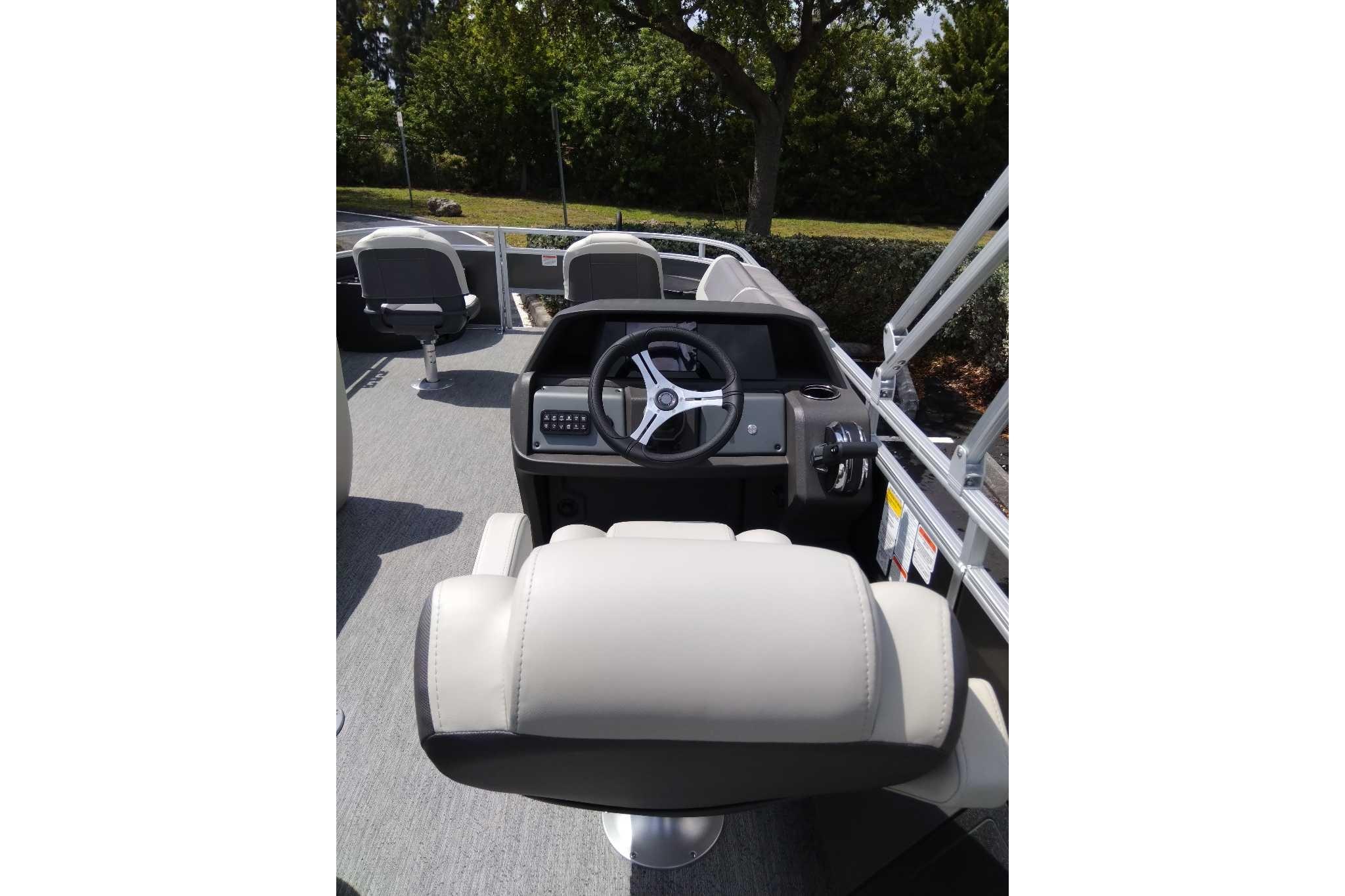 2026 Sun Tracker Fishin' Barge 22 DLX helm with steering wheel and seating.