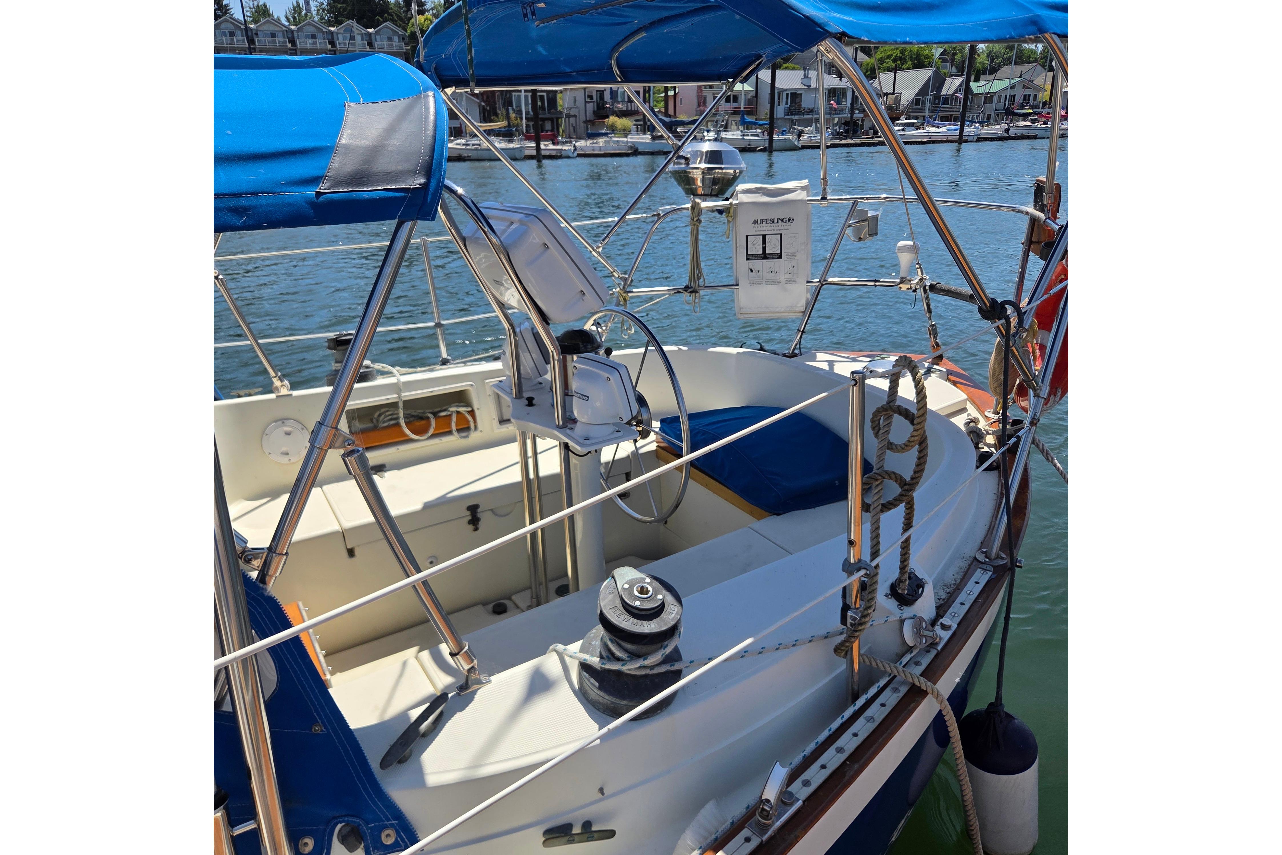 1983 Pacific Seacraft 34 sailboat cockpit with blue canopy, docked in a marina.