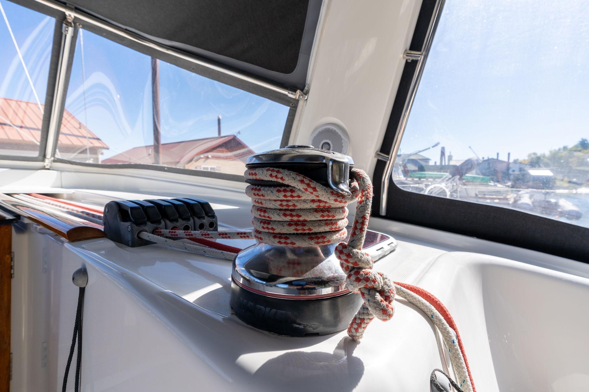 Winch and ropes on 2013 Beneteau Oceanis 50 sailboat deck, sunny day.