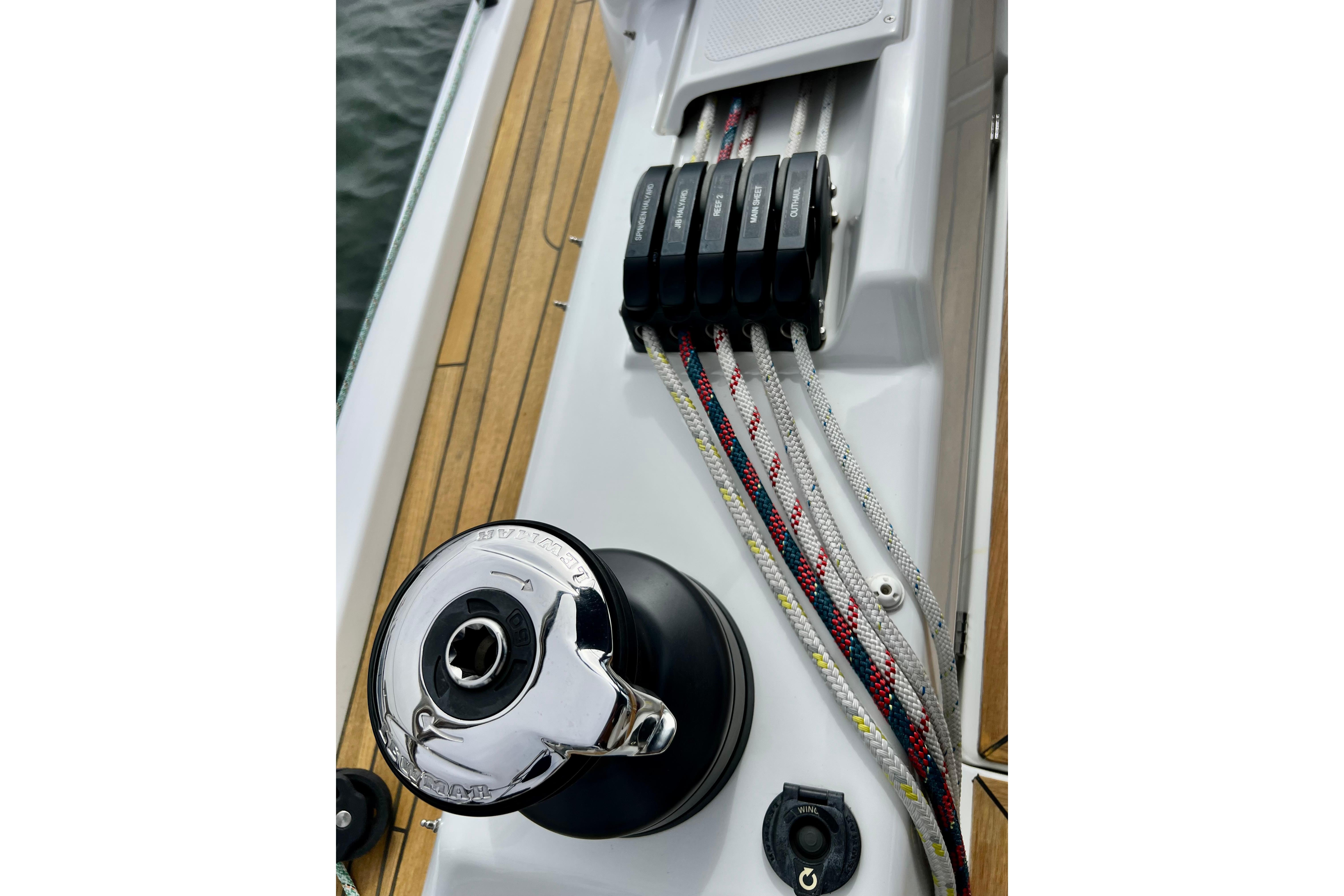 Close-up of 2016 Hanse 455 sailboat deck with winch and colorful ropes.