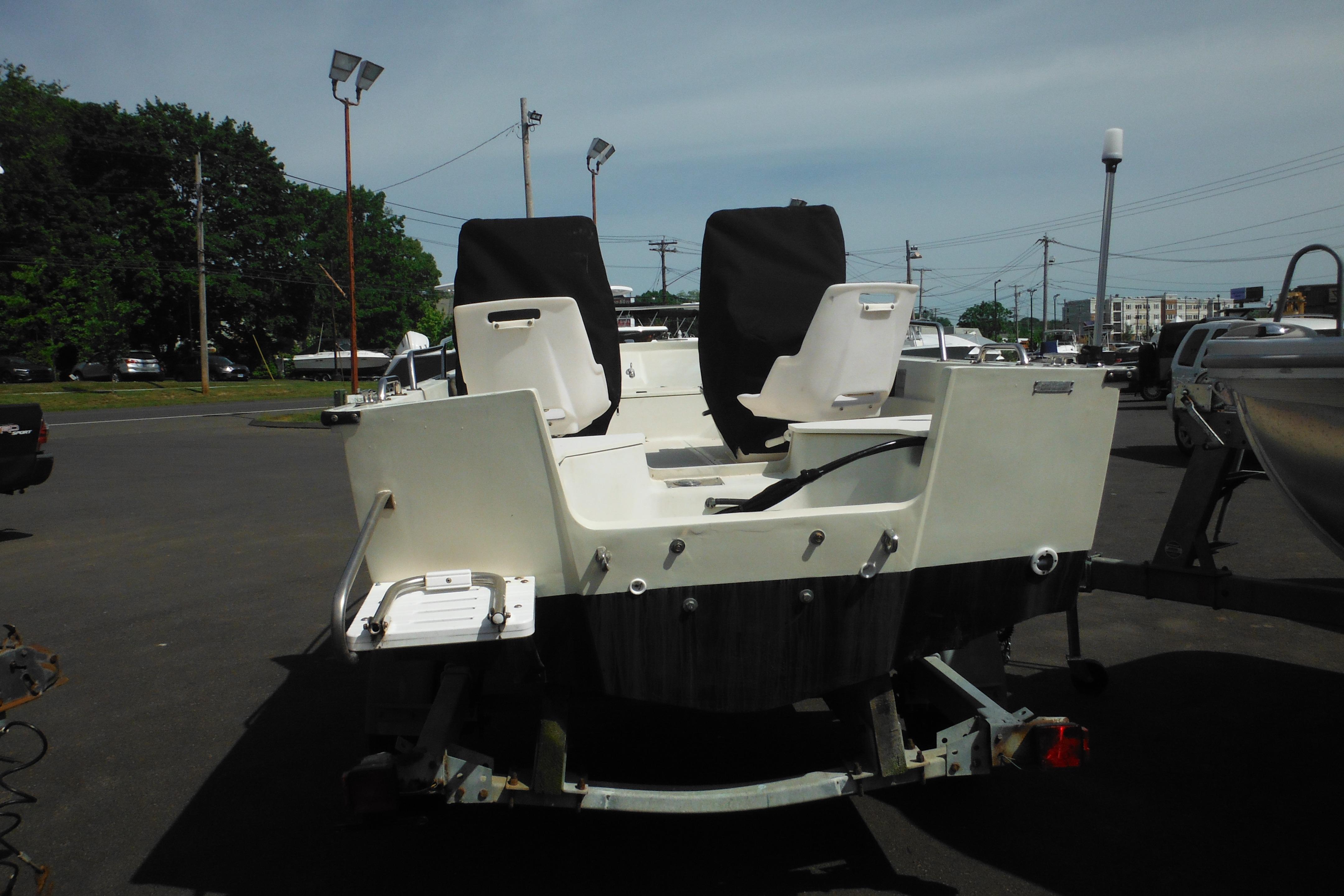 1991 Boston Whaler 16 SL boat on trailer, rear view in parking lot.
