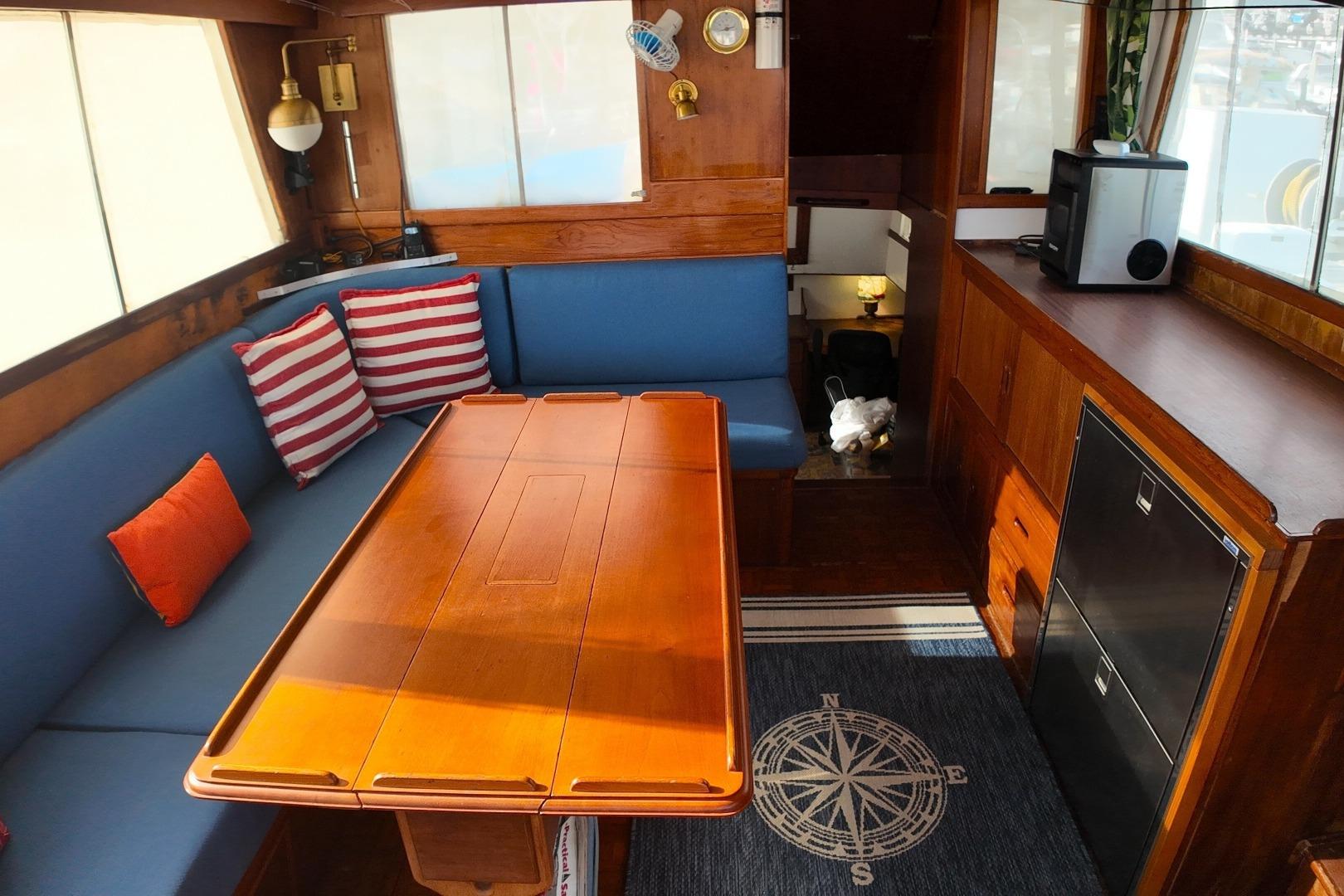 Interior of a 1978 Grand Banks 42 Classic yacht with wooden table and blue seating.