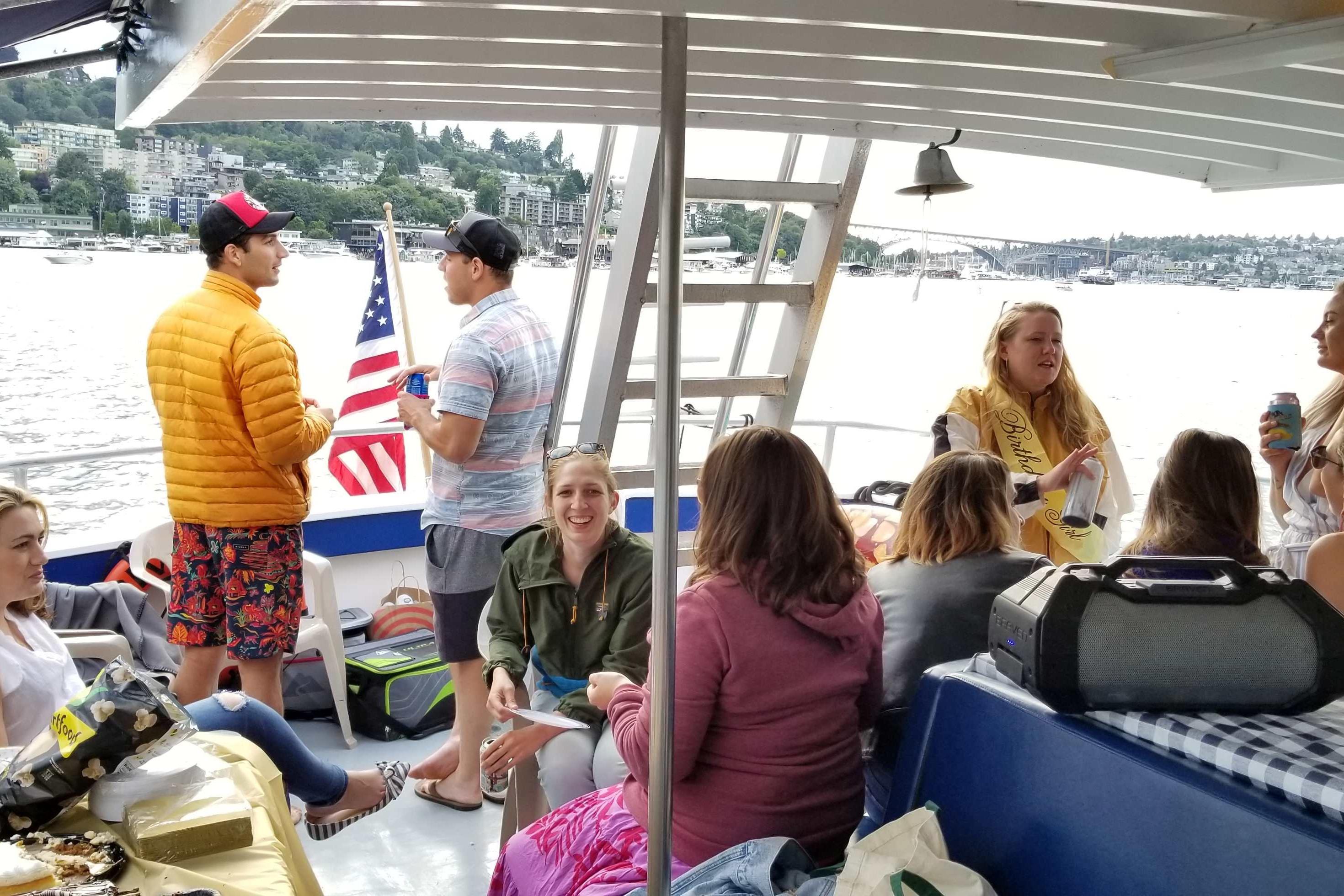 Group enjoying a party on a 1964 Grandy Tour Boat with scenic waterfront views.