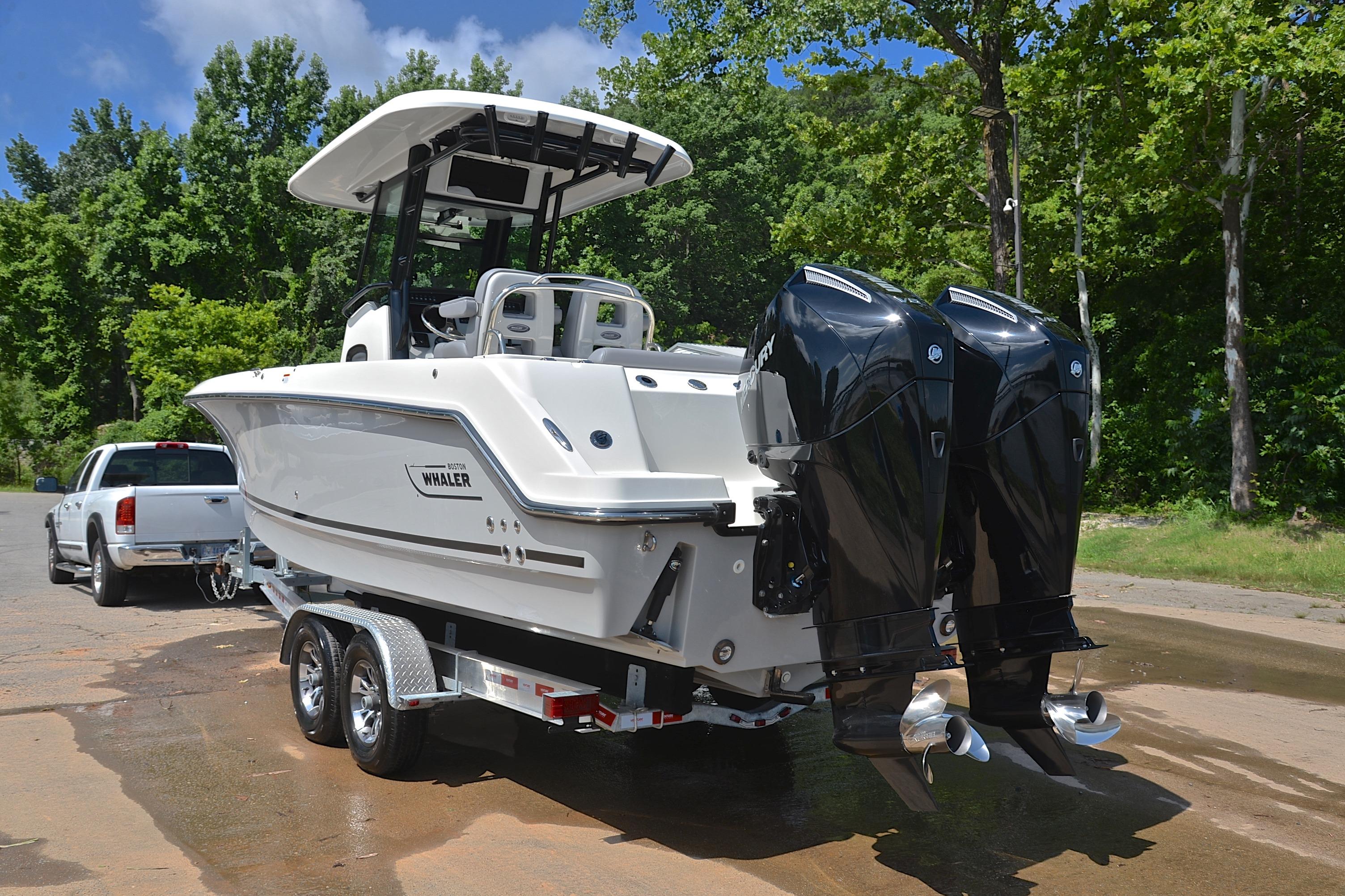 2024 Boston Whaler 250 Outrage boat on trailer, dual engines, parked near trees.