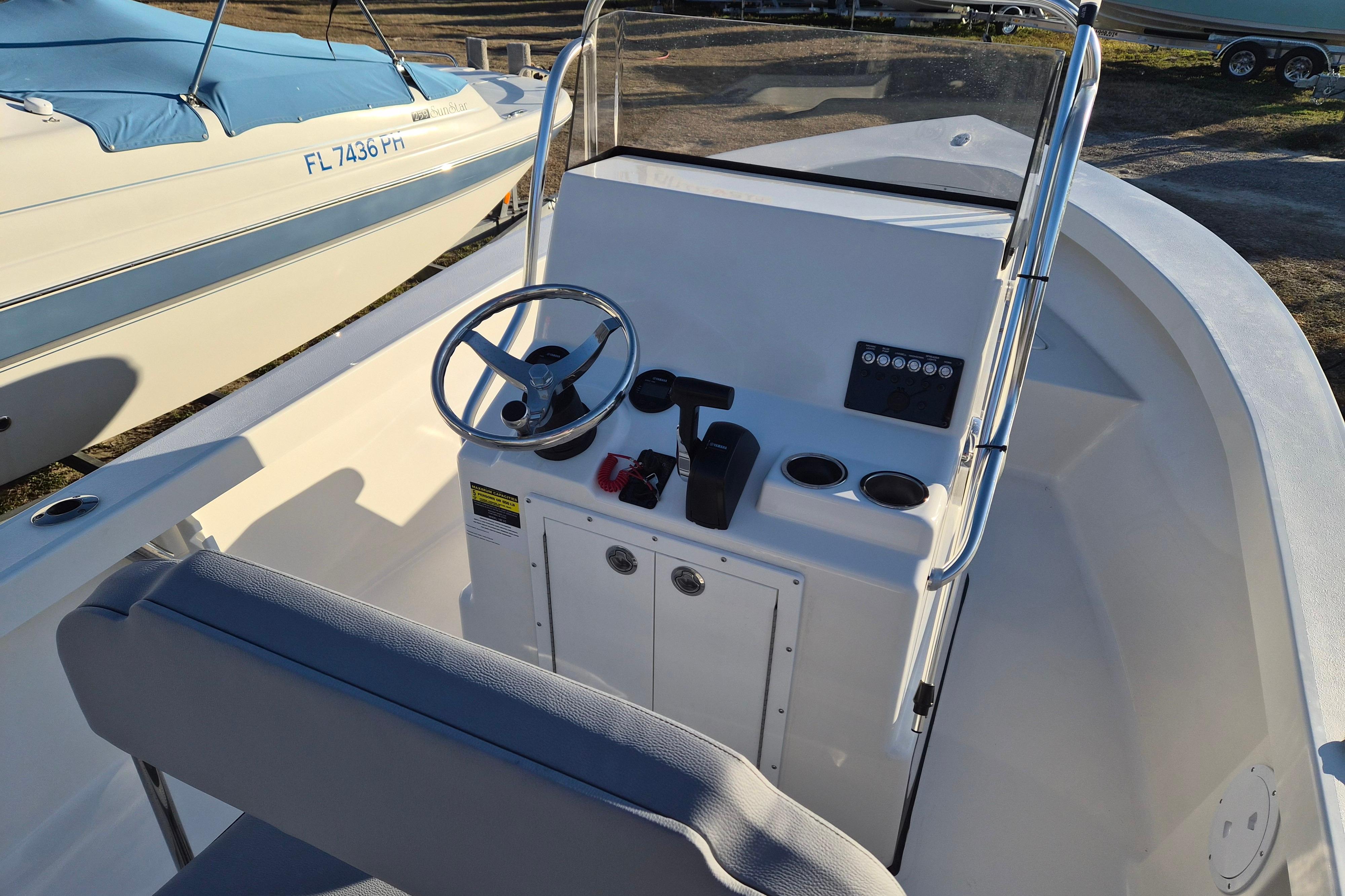 2026 May-Craft 192 boat console with steering wheel and controls, docked beside another boat.