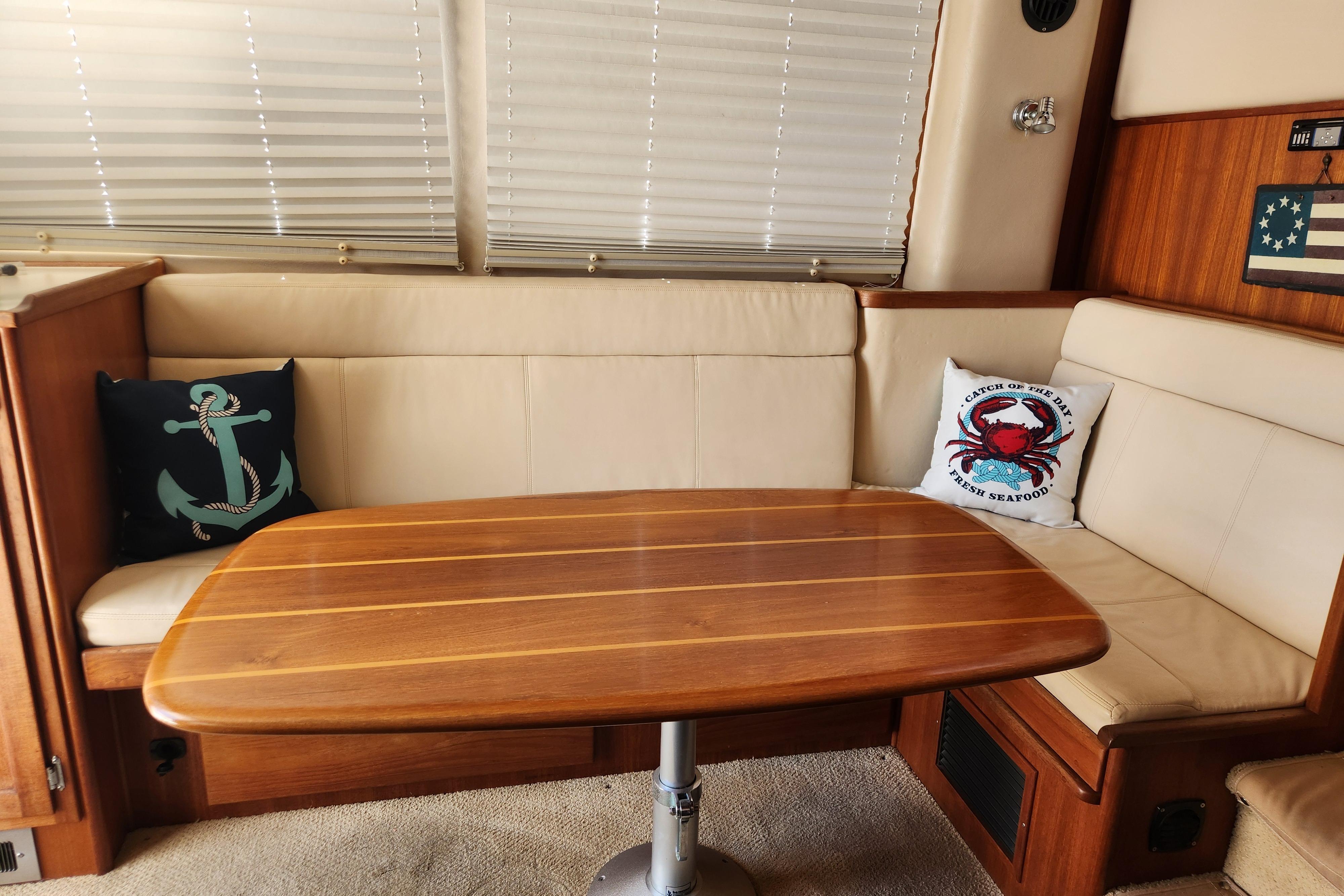 Interior of 2006 American Tug AT with wooden table and nautical-themed cushions.