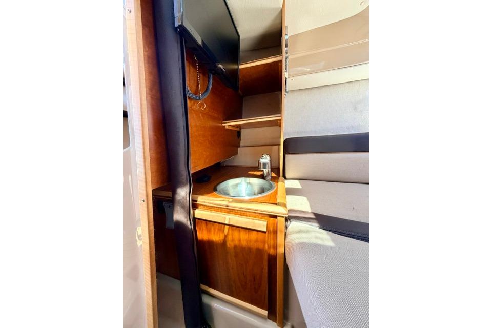 Interior of 2017 Cutwater C-242 Coupe featuring a compact sink and wooden cabinetry.