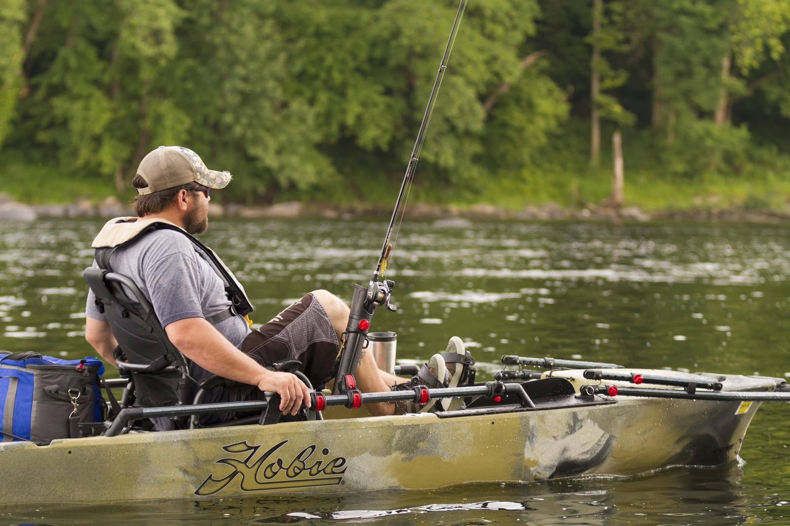 Man fishing on a 2023 Hobie Pro Angler 12 kayak in a serene lake.