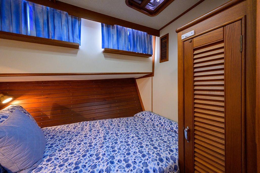 Cozy cabin interior of 1999 Grand Banks 42 Europa with wooden paneling and blue accents.