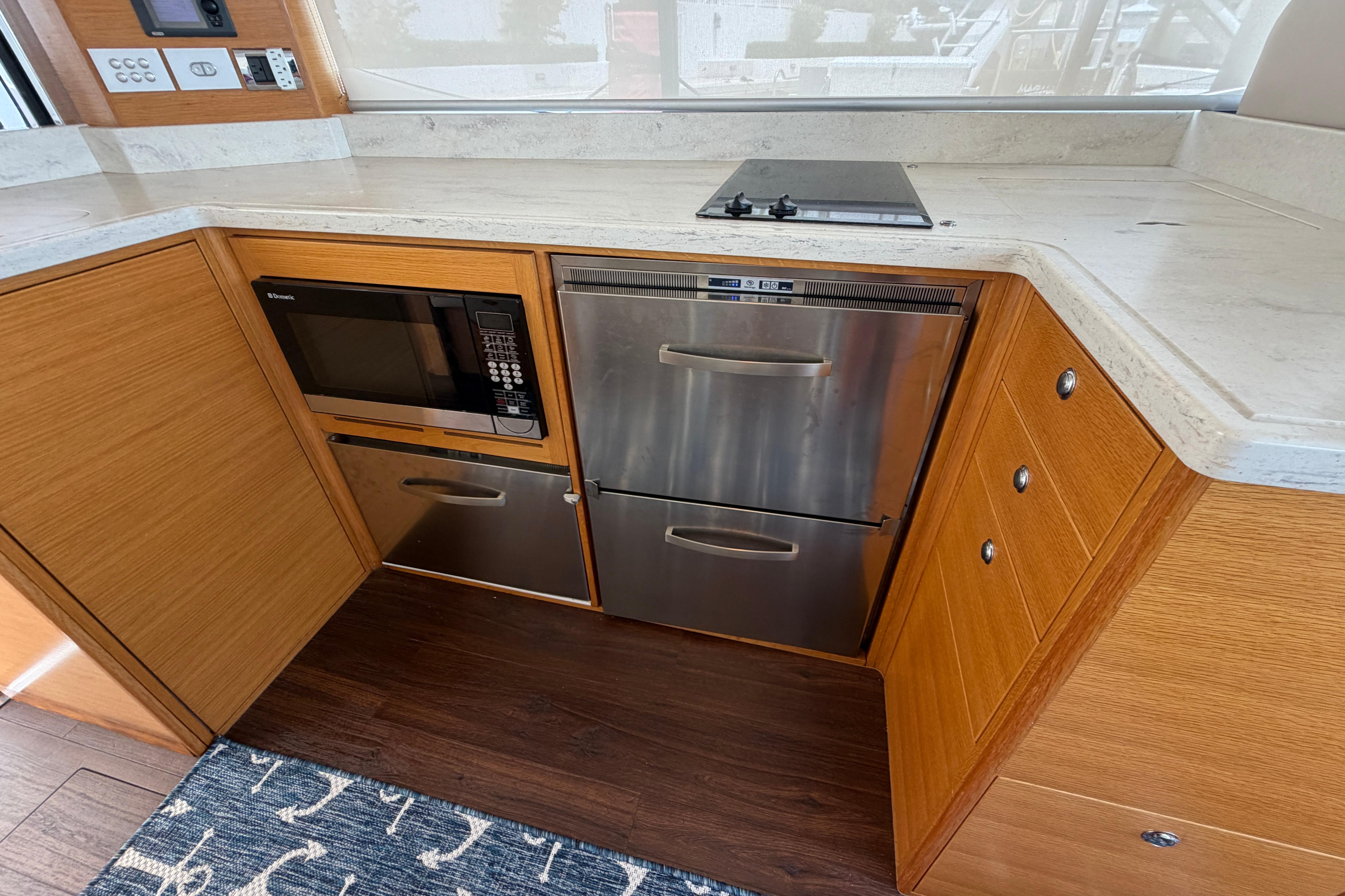 Modern kitchen in 2015 Riviera 445 SUV with microwave, stove, and stainless steel drawers.