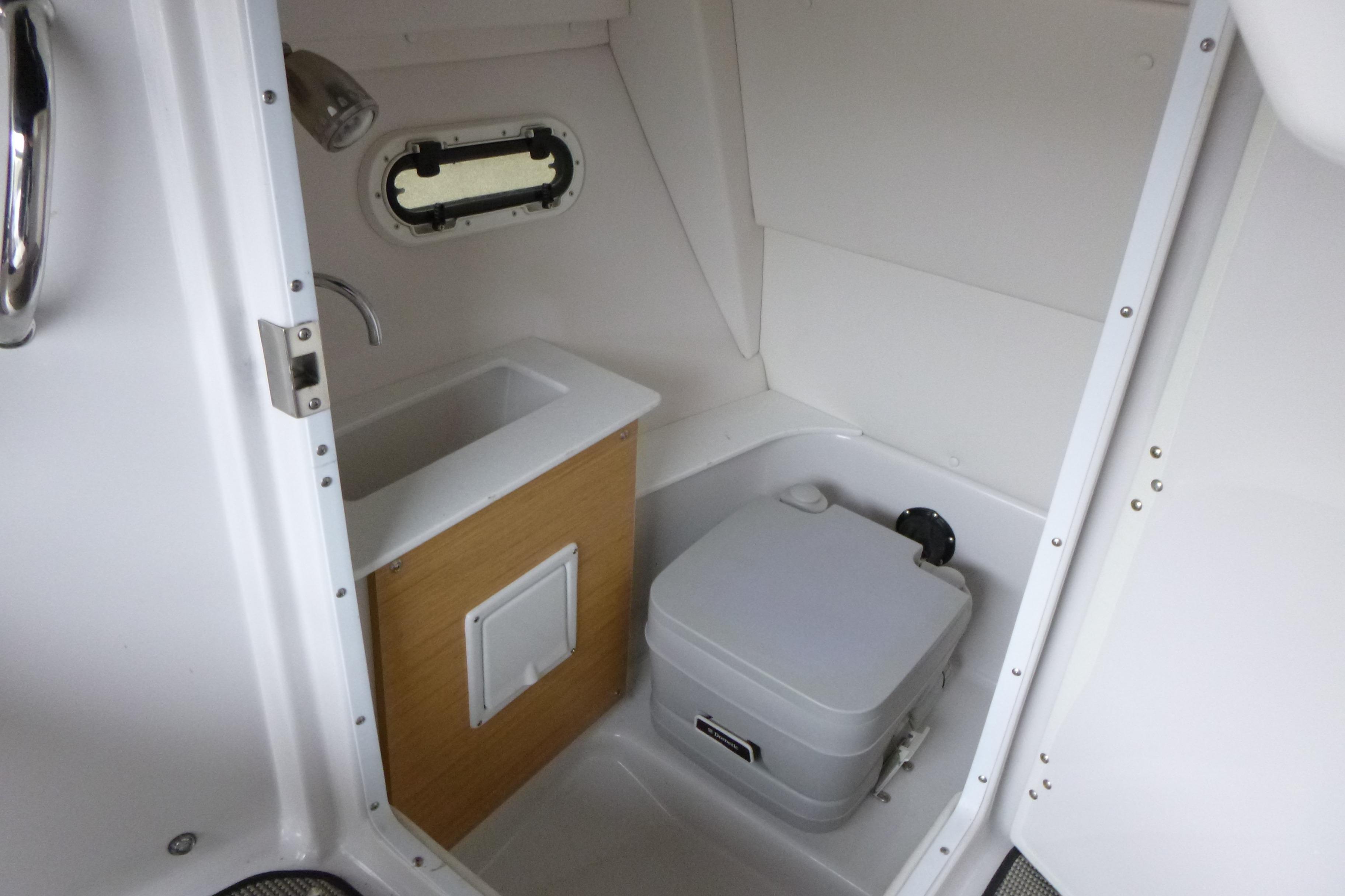 Compact bathroom in 2017 Four Winns H260 boat with sink and portable toilet.