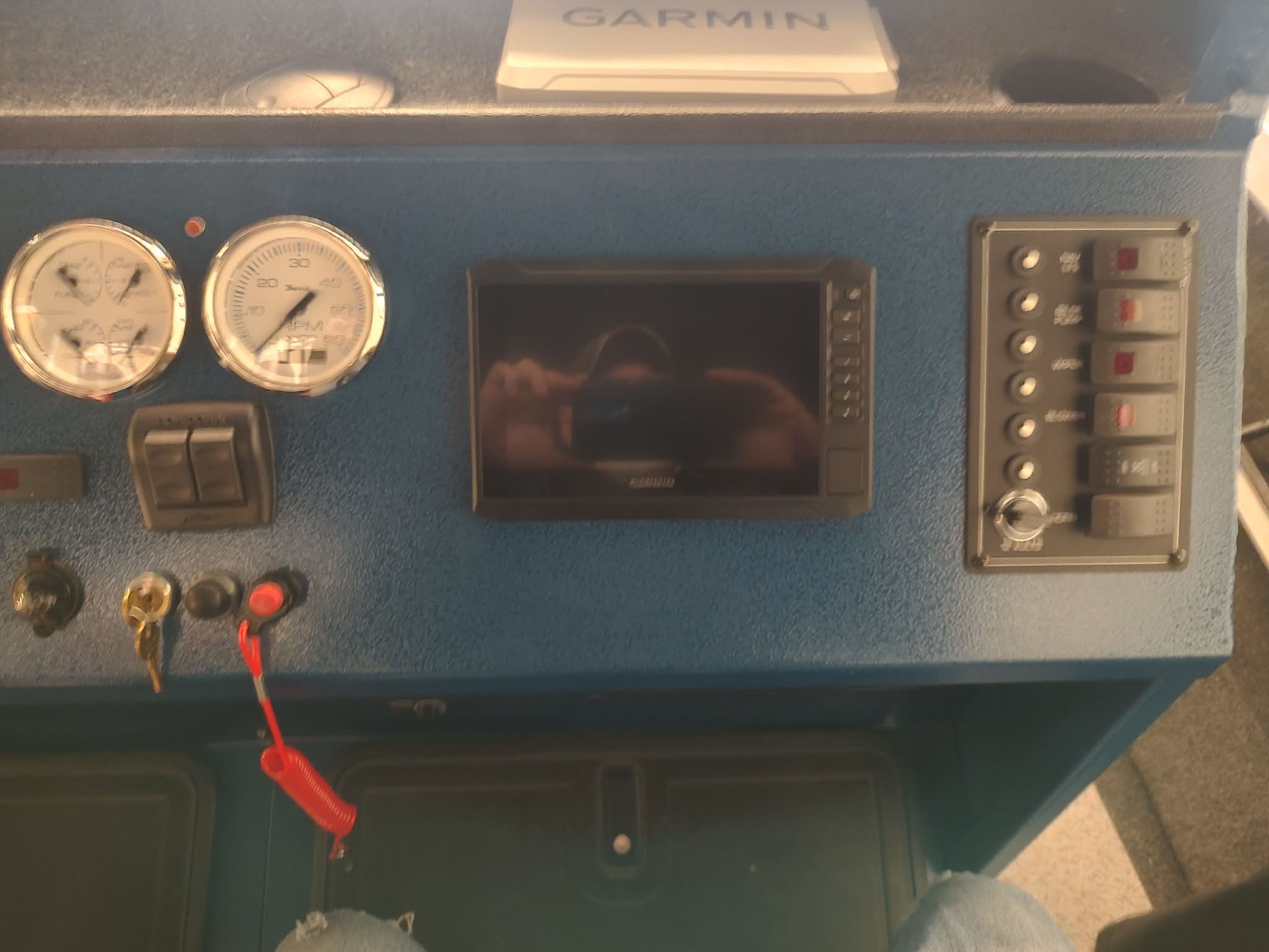 The image shows a boat dashboard with instruments and a screen.