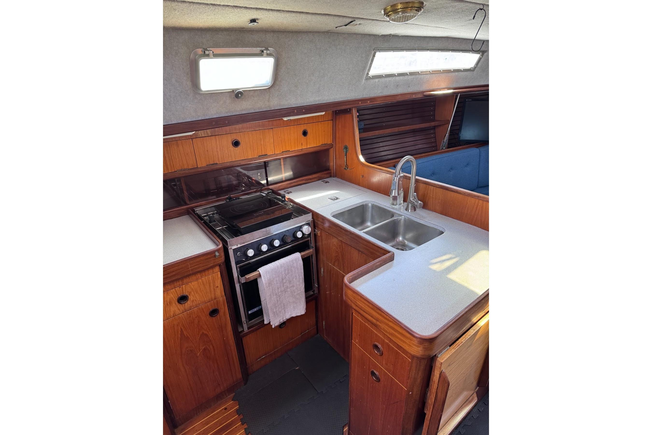 Interior of 1985 Beneteau First 375 yacht, featuring a compact kitchen with stove and sink.