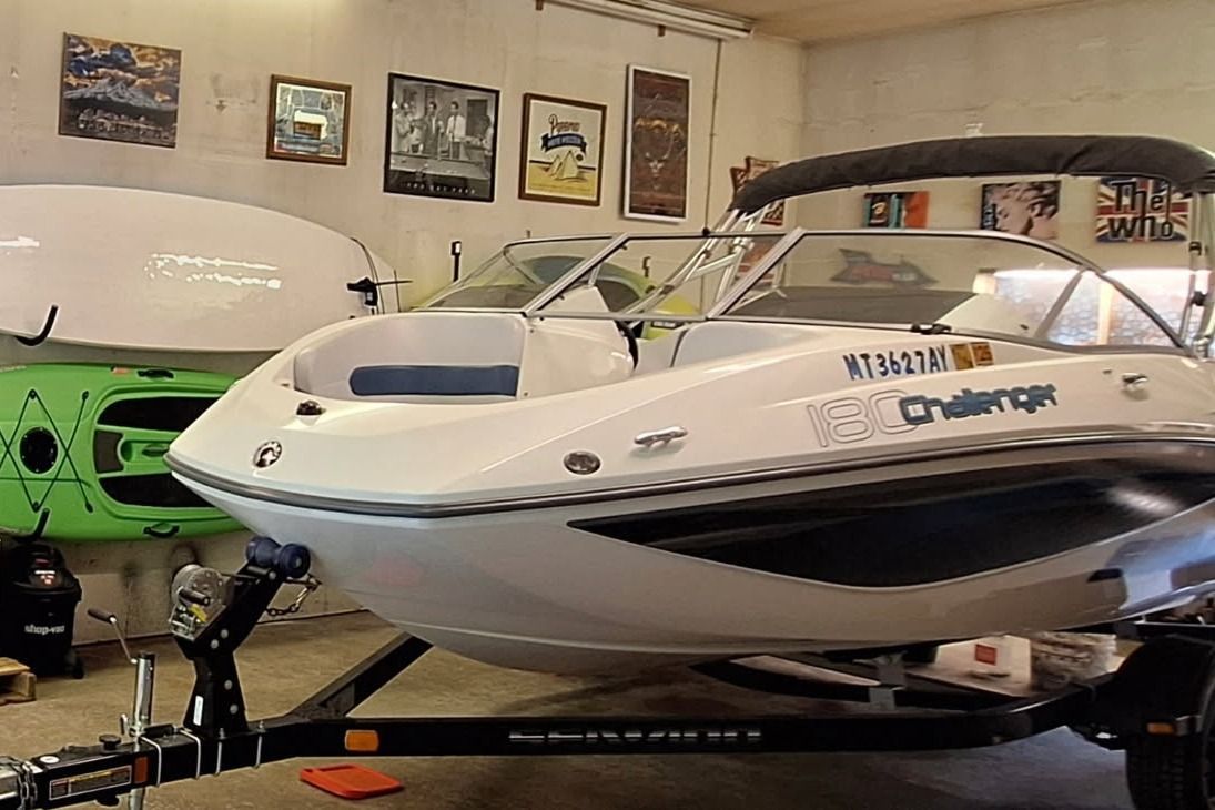 A white 2007 Sea-Doo 180 Challenger boat on a trailer in a garage.
