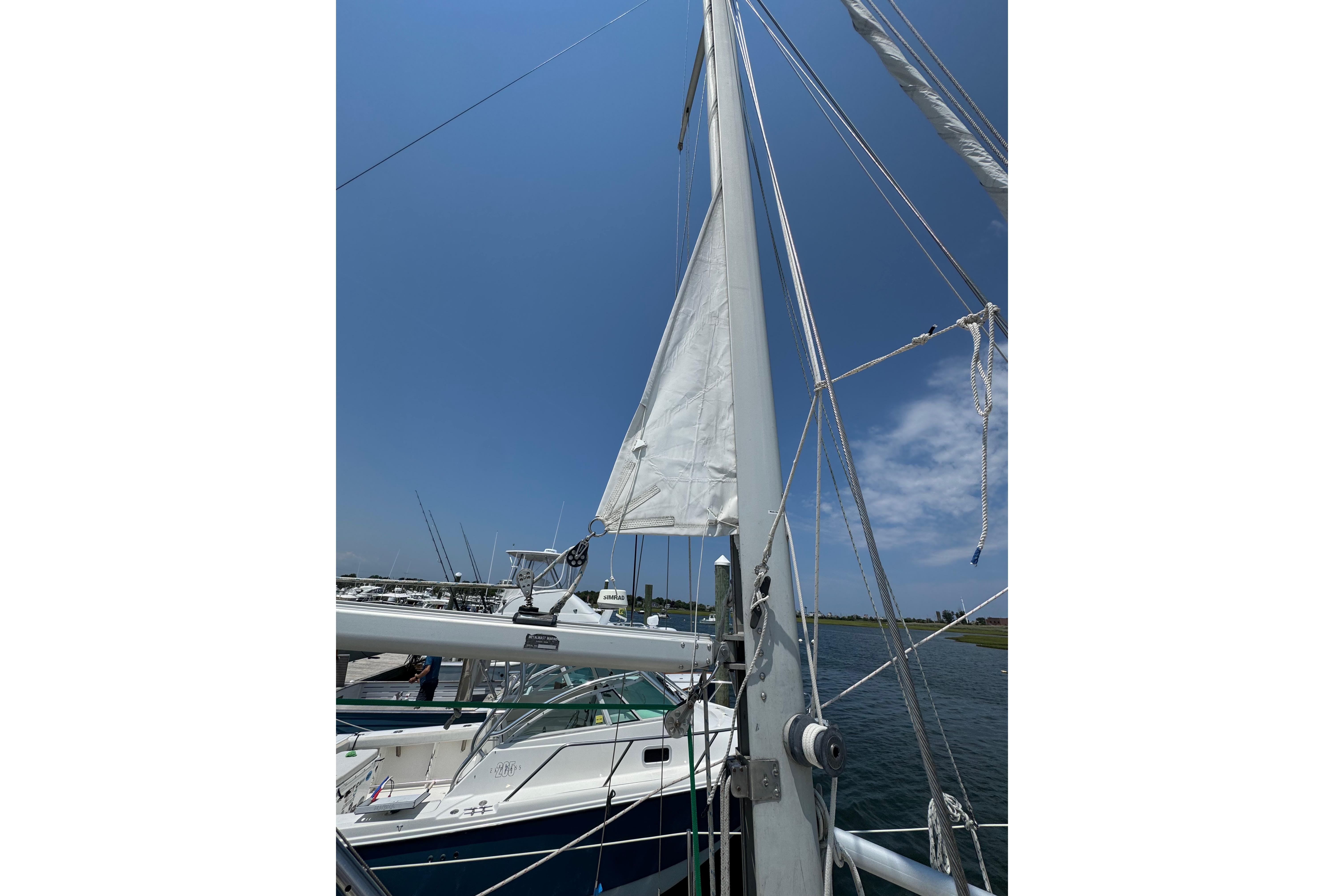 Cape Dory 30 Motorsailer 1989 with sails raised, docked under clear blue sky.