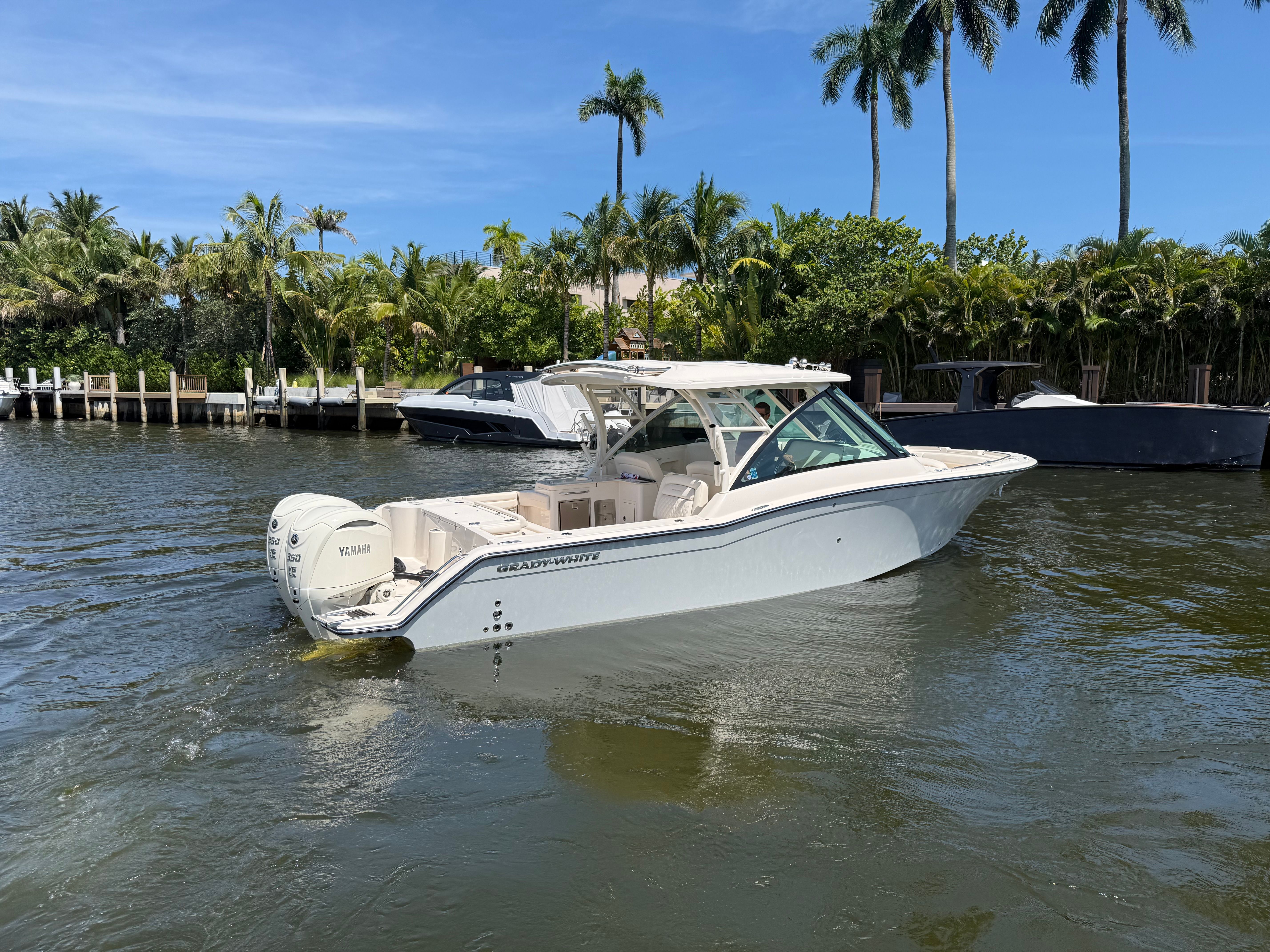 2027 Grady-White Freedom 325 on a calm waterway with palm trees in the background.