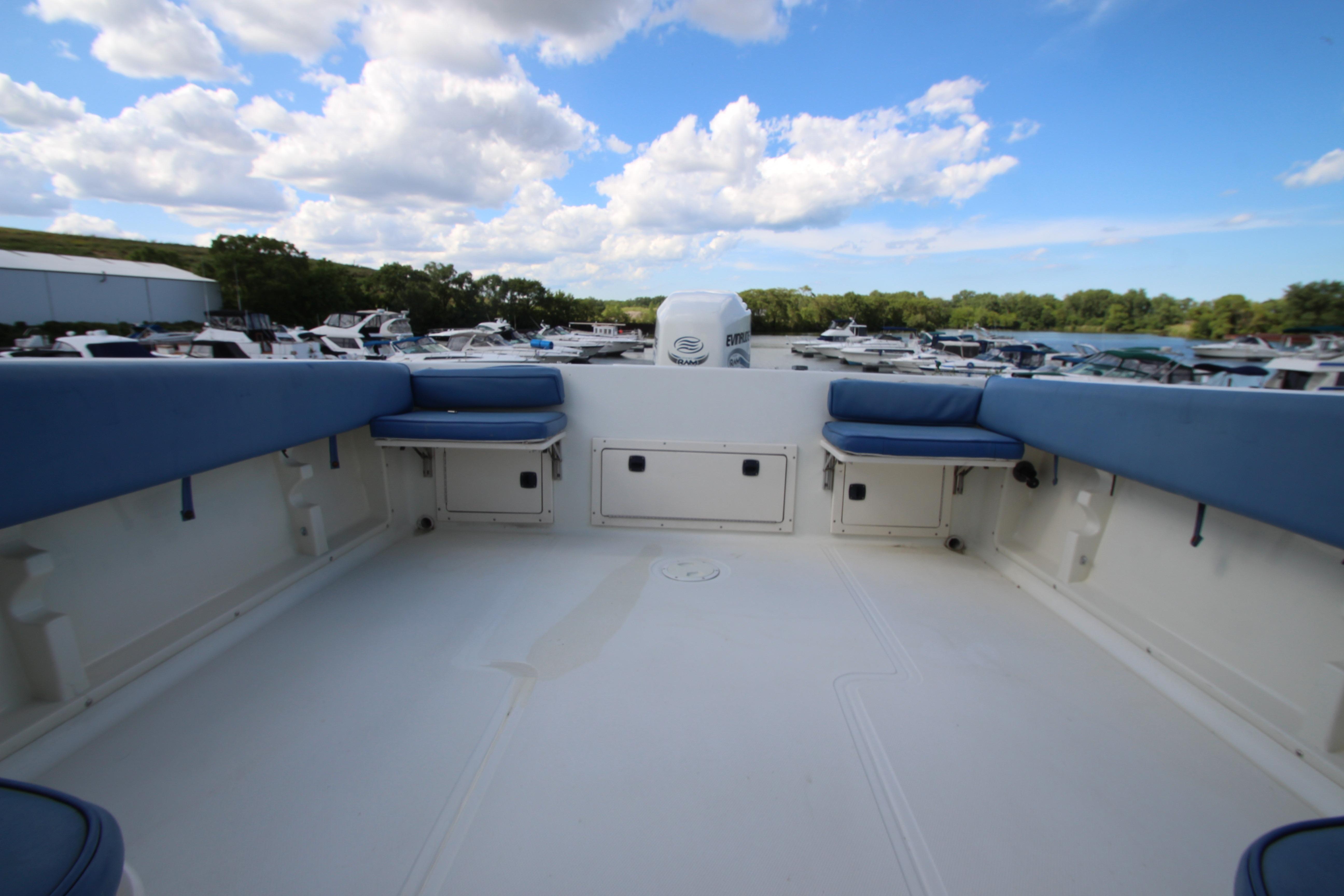 2002 Hydra-Sports 230 WA boat interior with blue seating, docked at a marina under a cloudy sky.