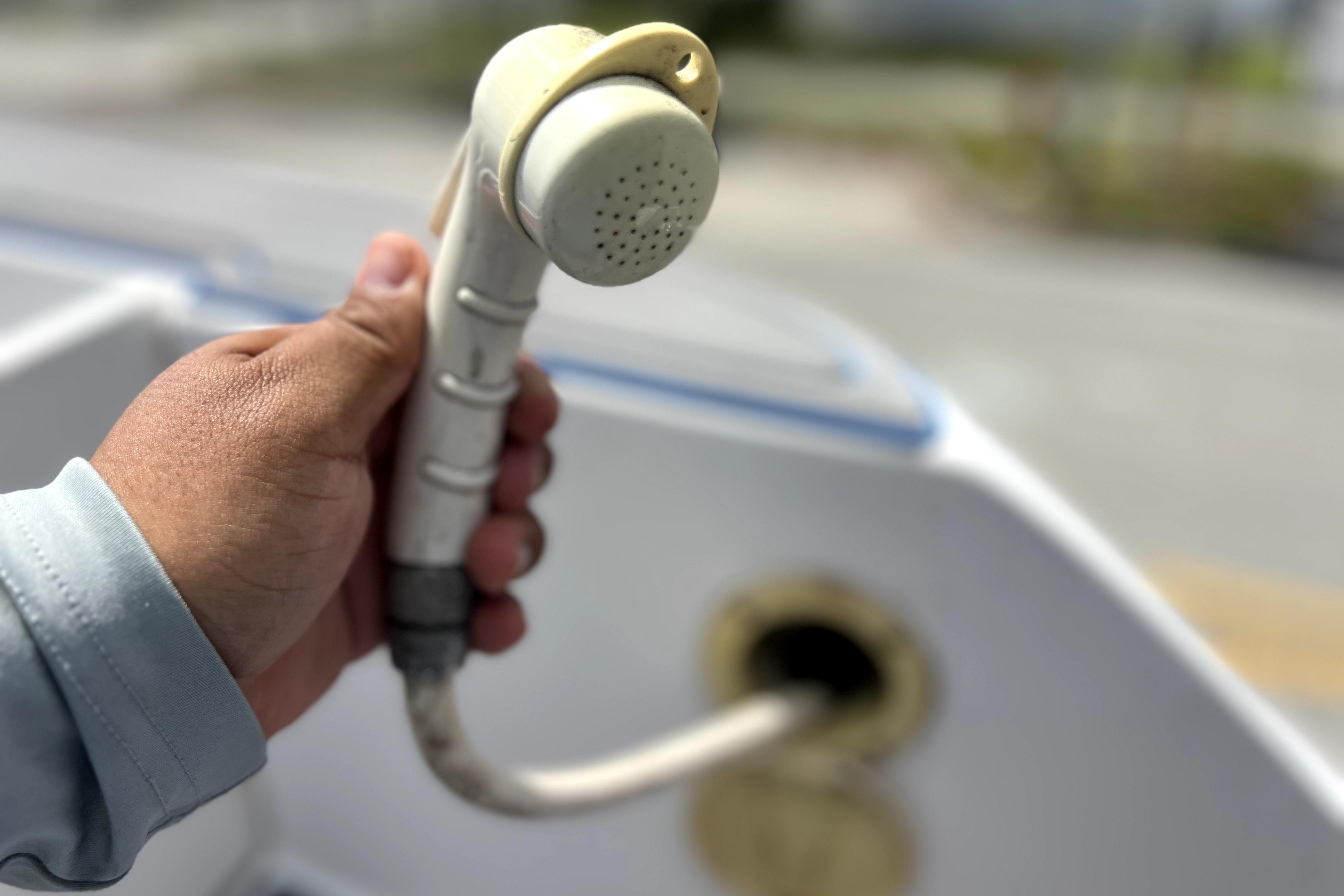 Hand holding a showerhead on a 2007 Wellcraft 35 Scarab Sport Open boat.
