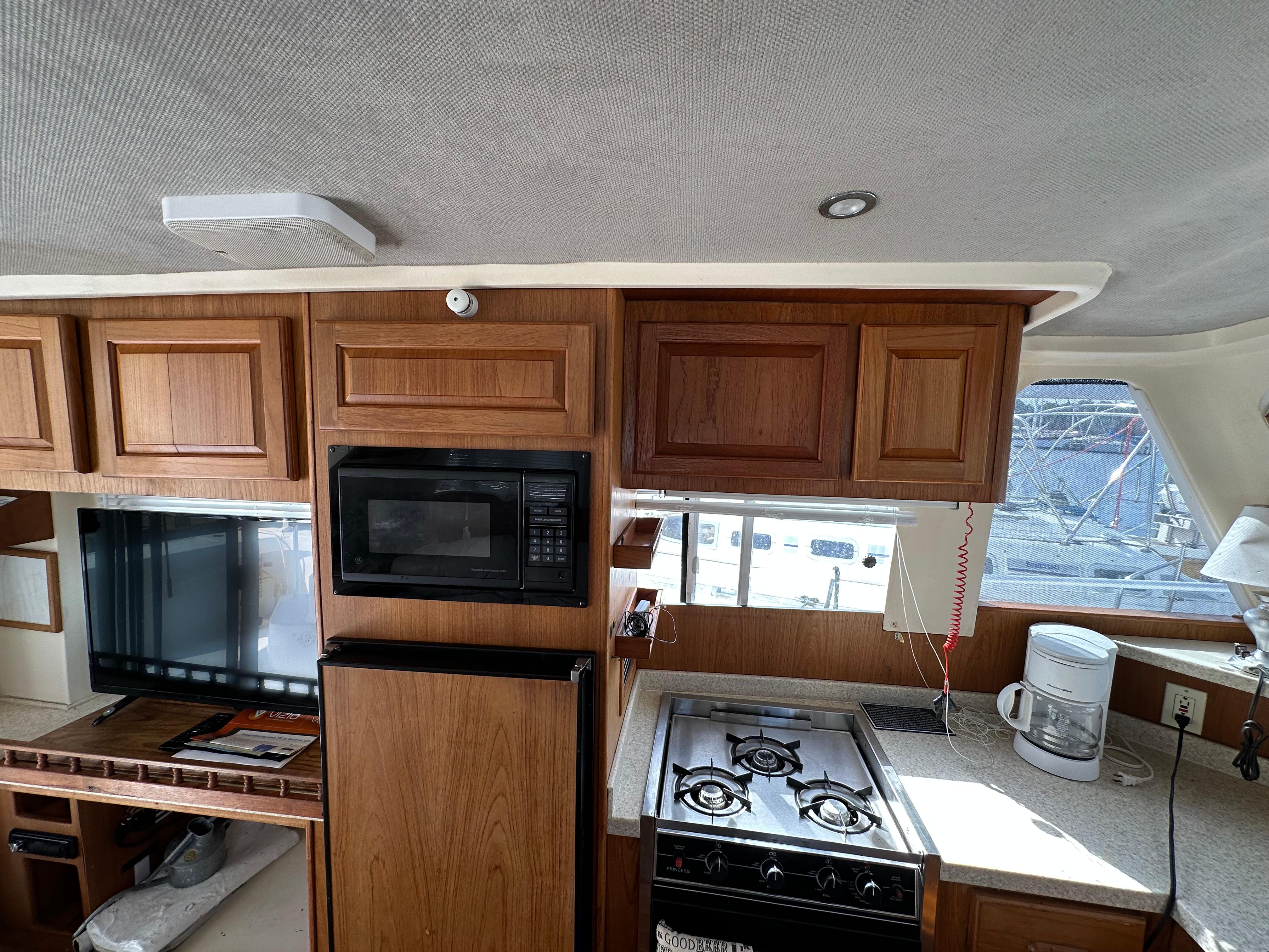 1998 Mainship 350 Trawler kitchen with wood cabinets, stove, microwave, and countertop appliances.