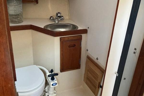 1989 Catalina 30 yacht bathroom with sink, toilet, and wooden cabinetry.