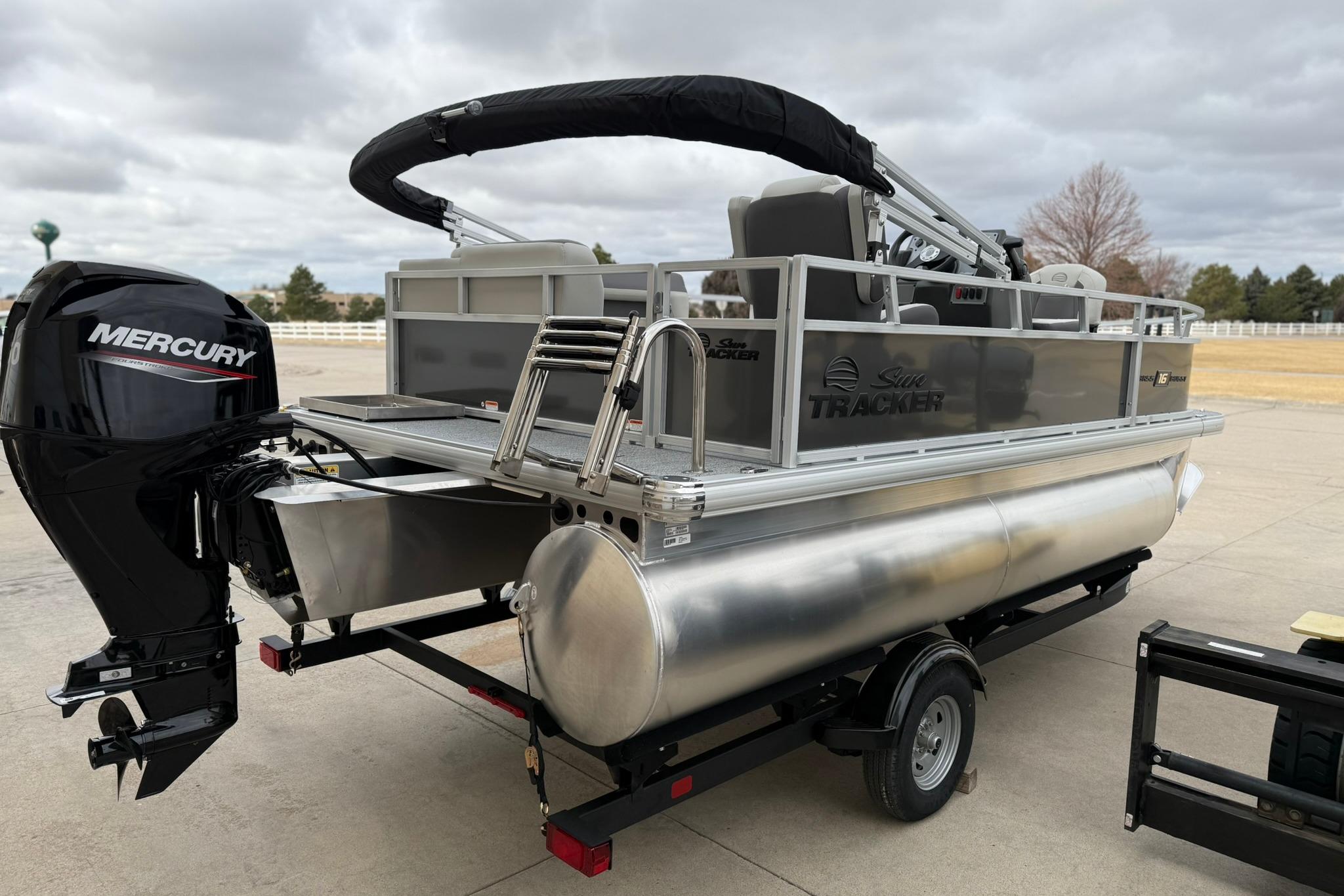 2026 Sun Tracker Bass Buggy 16 XL Select pontoon boat with Mercury engine on trailer.