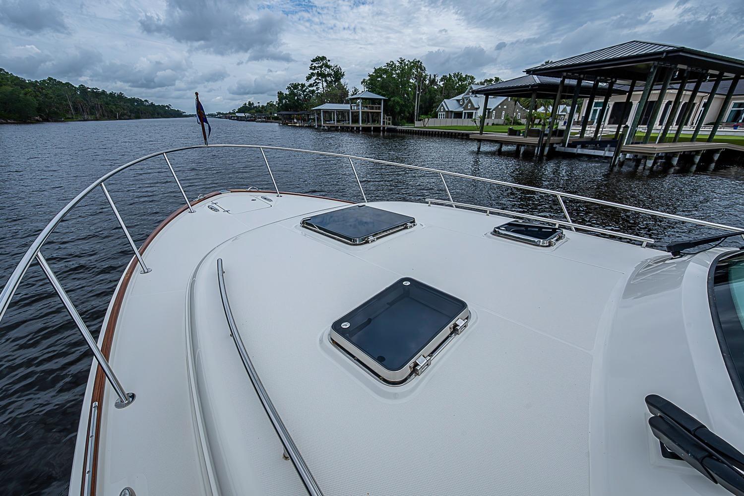 2023 Hinckley Sport Boat 40 X on a serene river with docks and trees.